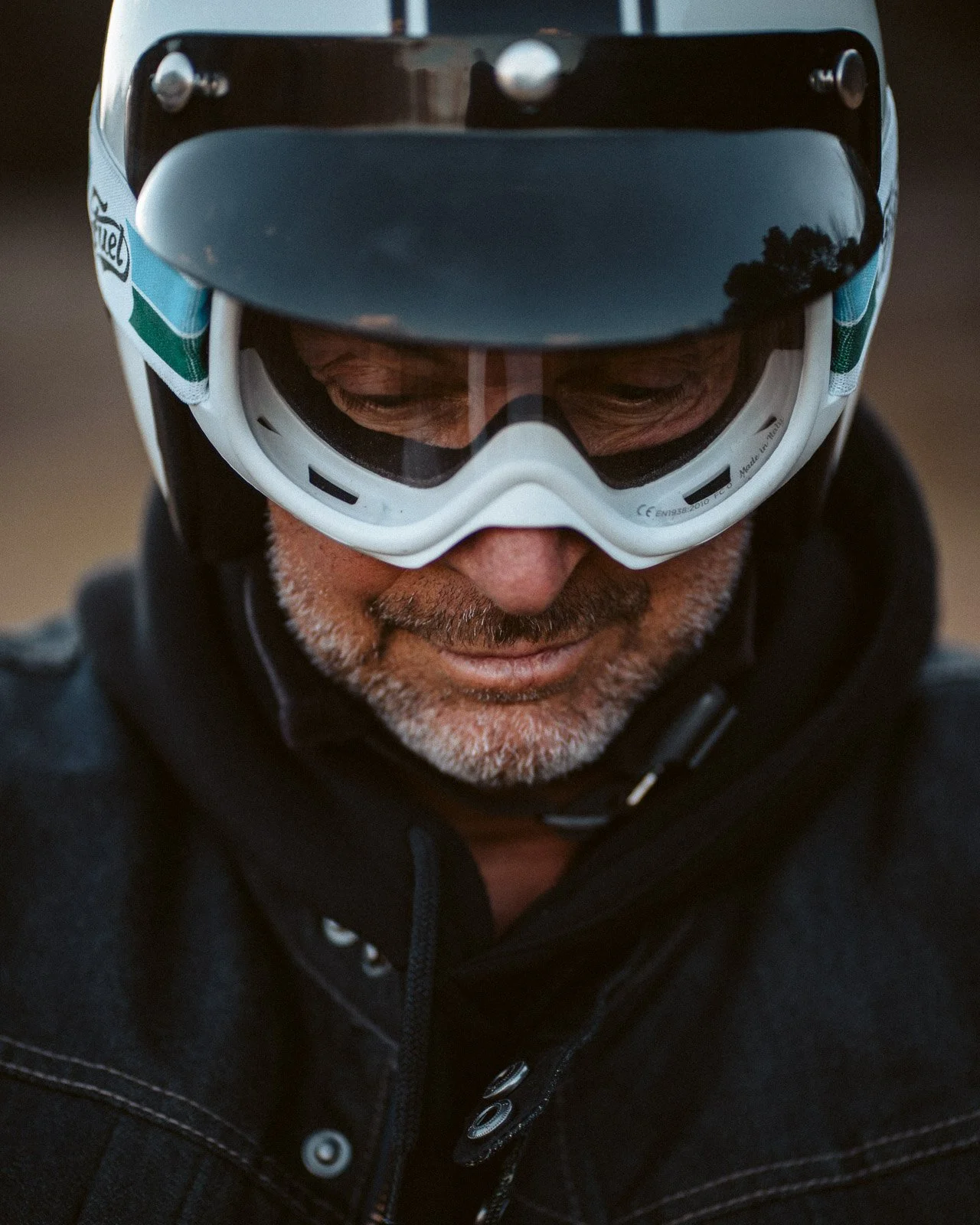 Nahaufnahme eines älteren Mannes mit Fahrradhelm und Schutzbrille, der nach unten schaut.