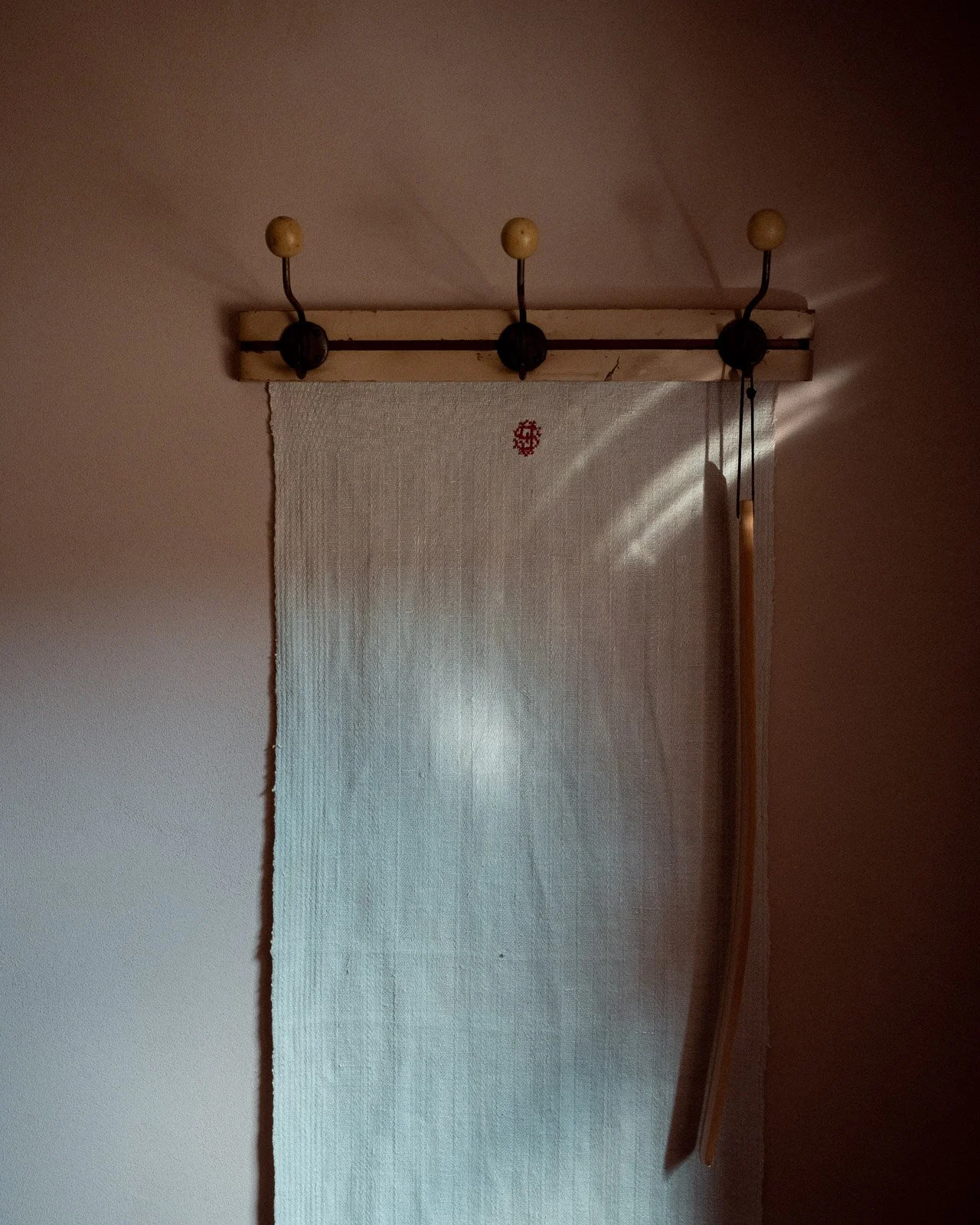 Kleiderhaken an einer Holzleiste mit Textil und Holzlöffel daran befestigt.