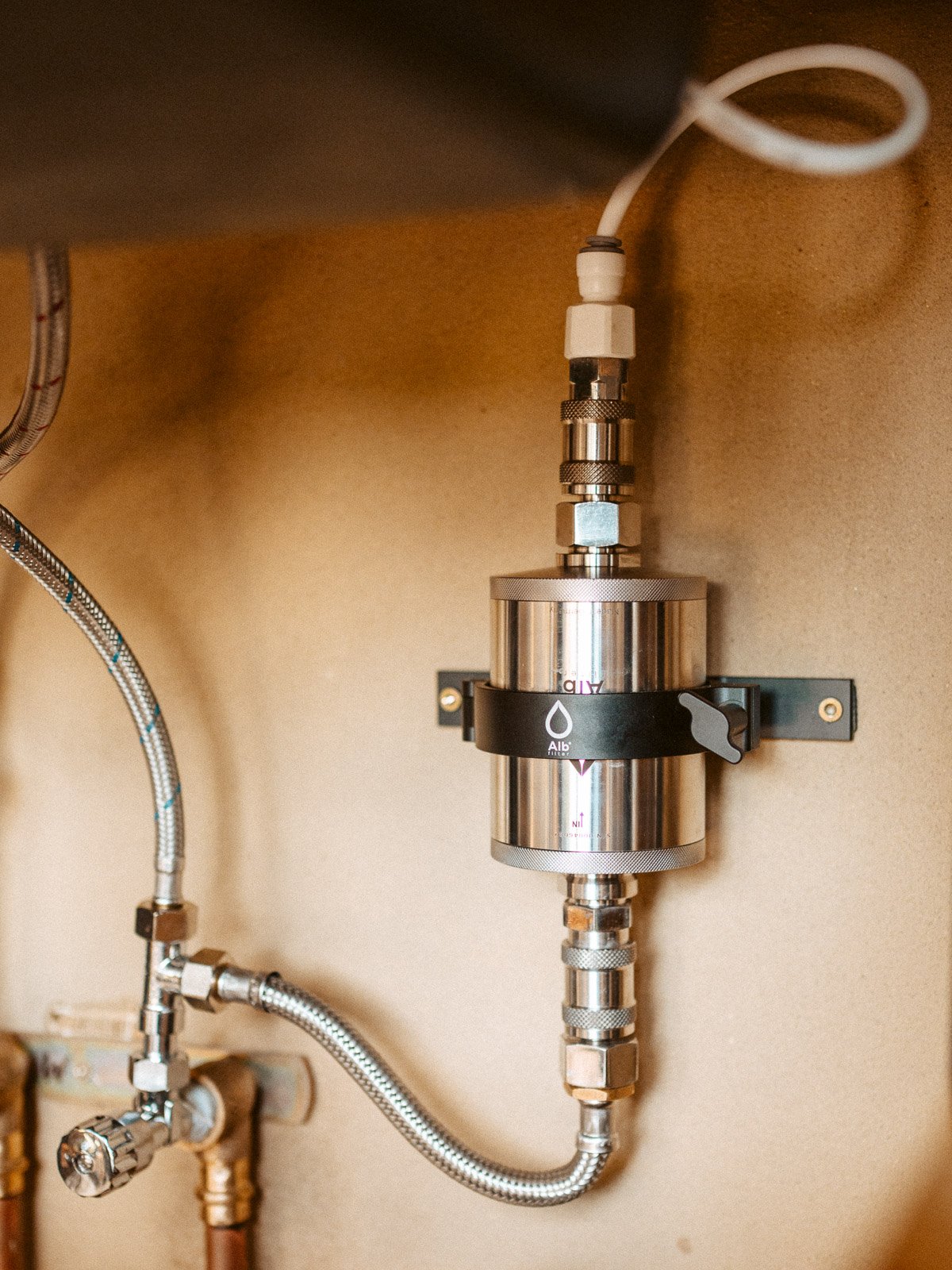 Ein metallischer Wasserregler mit Dichtungen und einer schwarzen Halterung an einer Wand.