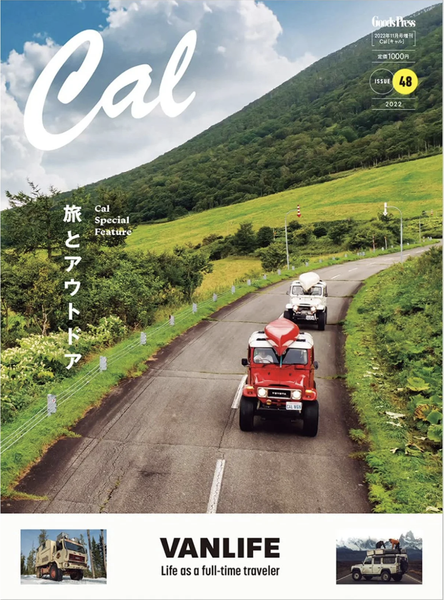 Ein Cover-Foto eines Magazins mit einer malerischen Route durch die grünen Hügellandschaften Kaliforniens, auf der zwei Fahrzeuge, ein roter Truck und ein weißer LKW, unterwegs sind. Das Magazin trägt den Titel 'Cal' und enthält Artikel über Kalifornien, Spezialitäten und Reisen. Es ist das 48. Heft aus dem Jahr 2022.