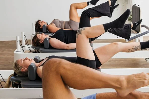 Women laying on their back during a reformer Pilates class in a studio in Bli Bli