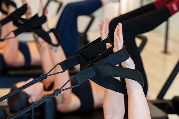 Group of women laying on their backs during a beginners reformer Pilates class in Buderim