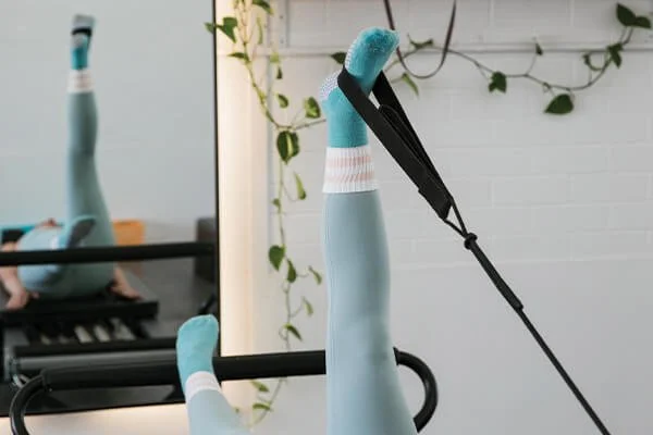 Woman extending her leg high during a class inside a reformer Pilates studio in Maroochydore