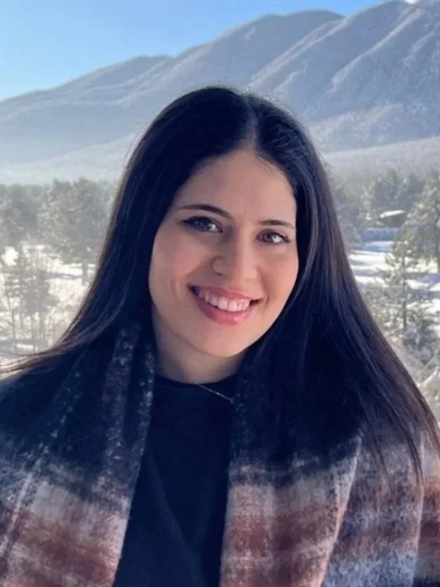 Young woman with dark hair smiling with mountains in the background