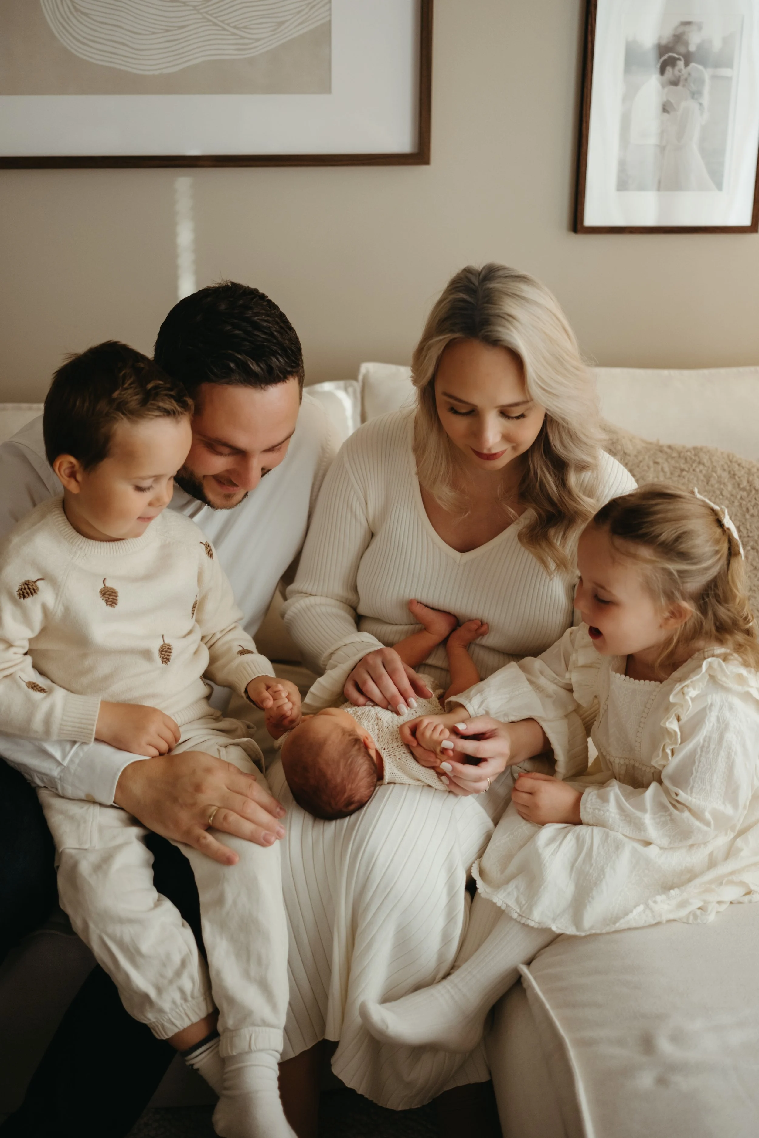 Familie samlet på sofa, med en nyfødt baby, mor, far og to barn.