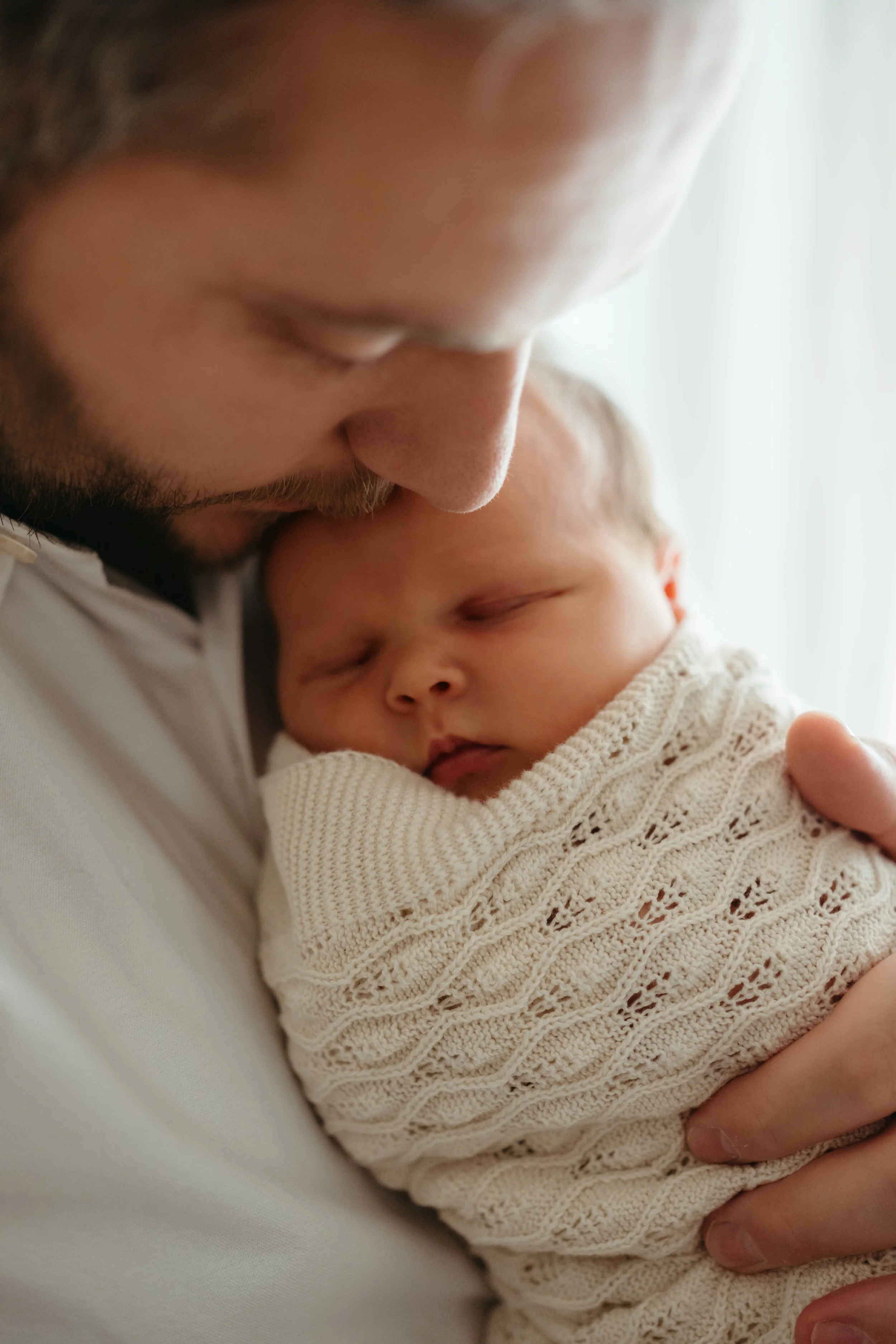 En mann holder en sovende baby inntil seg.