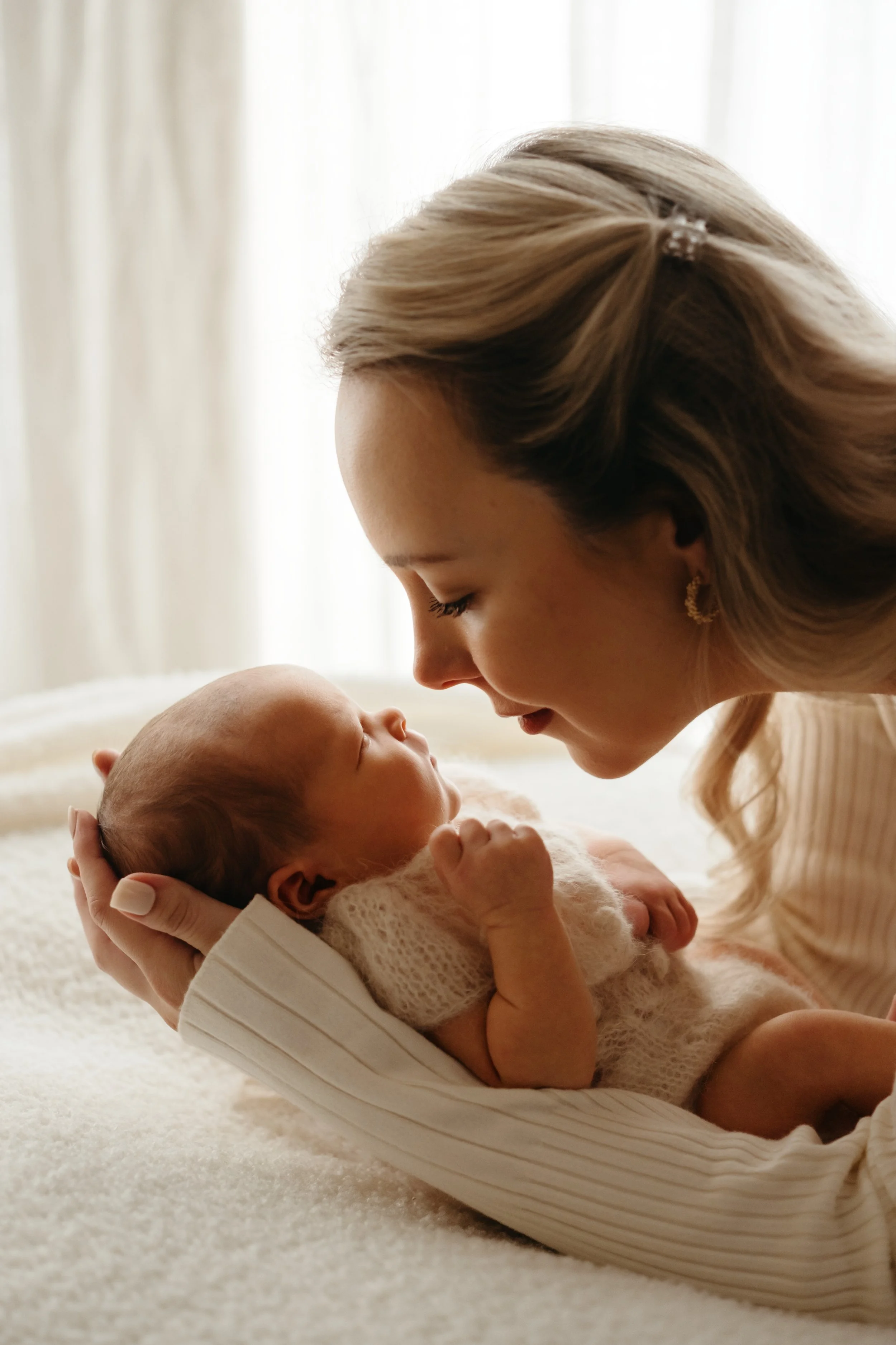 En kvinne holder en baby i hendene og ser nærmere på den.