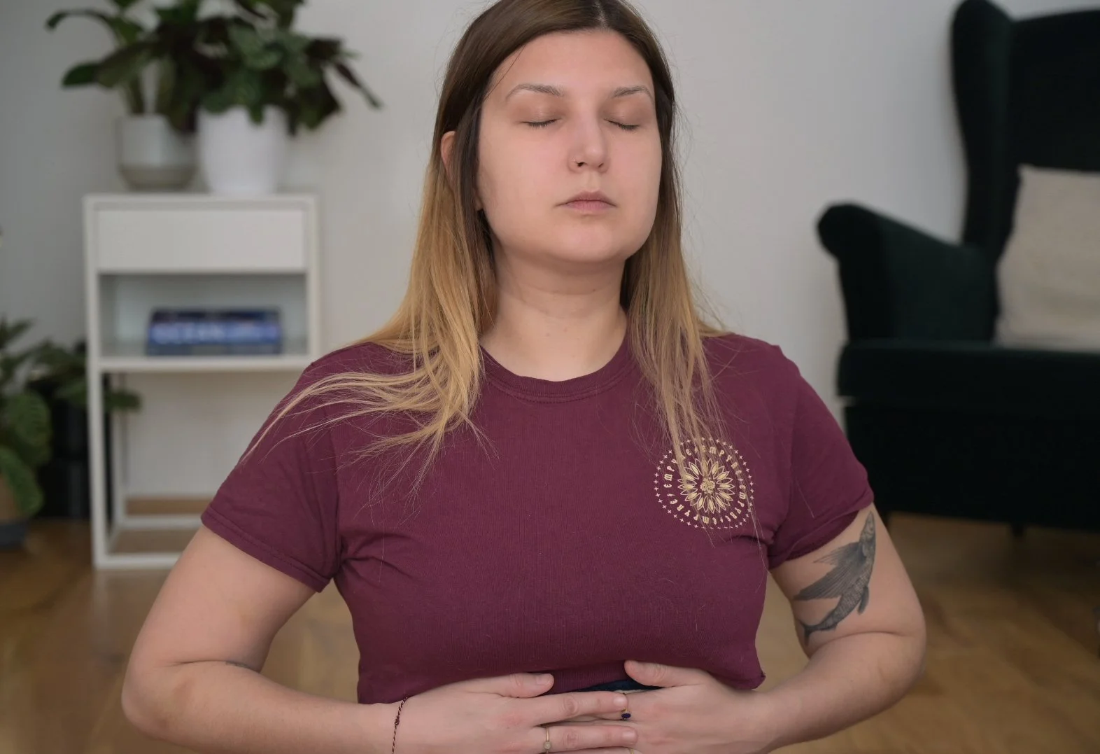 Eine Frau sitzt im Meditationssitz mit geschlossenen Augen und Haltung, die Konzentration oder Ruhe ausdrückt, während sie Breathwork macht.