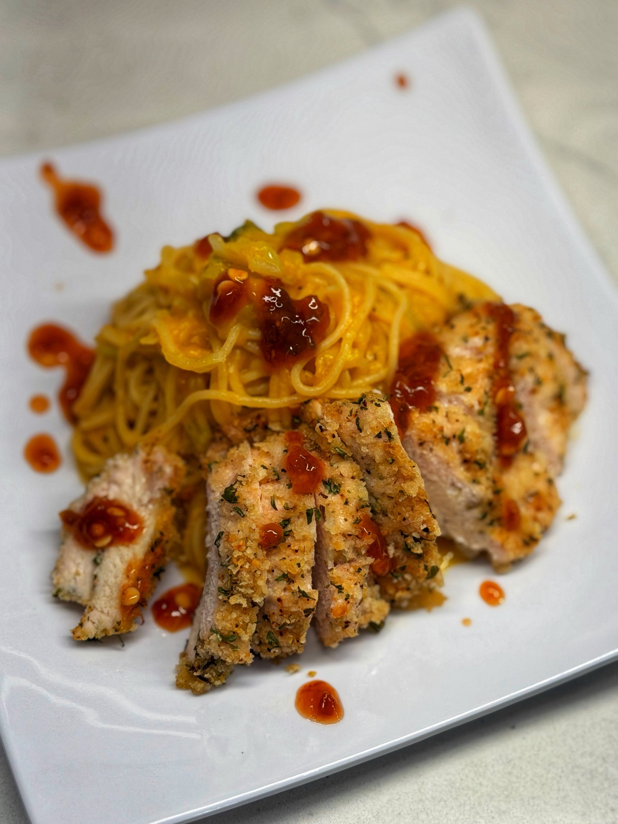 Summer squash and leak pasta topped with  baked chicken and chili crunch oil
