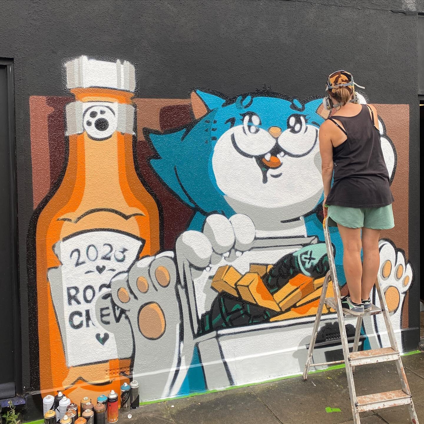 @roo_art is busy creating a fish and chip@eating cat on the side of the @the.corner.collective. If fish and chips isn&rsquo;t your bag but pizza is, we&rsquo;re giving away a slice of pizza in exchange for your feedback of the festival. It&rsquo;s ou