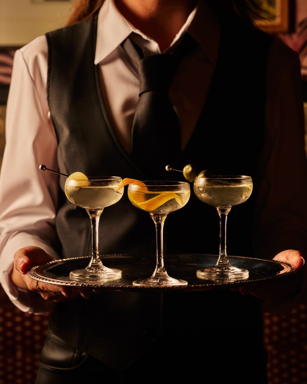 A server carrying three cocktails on a tray through Left Door