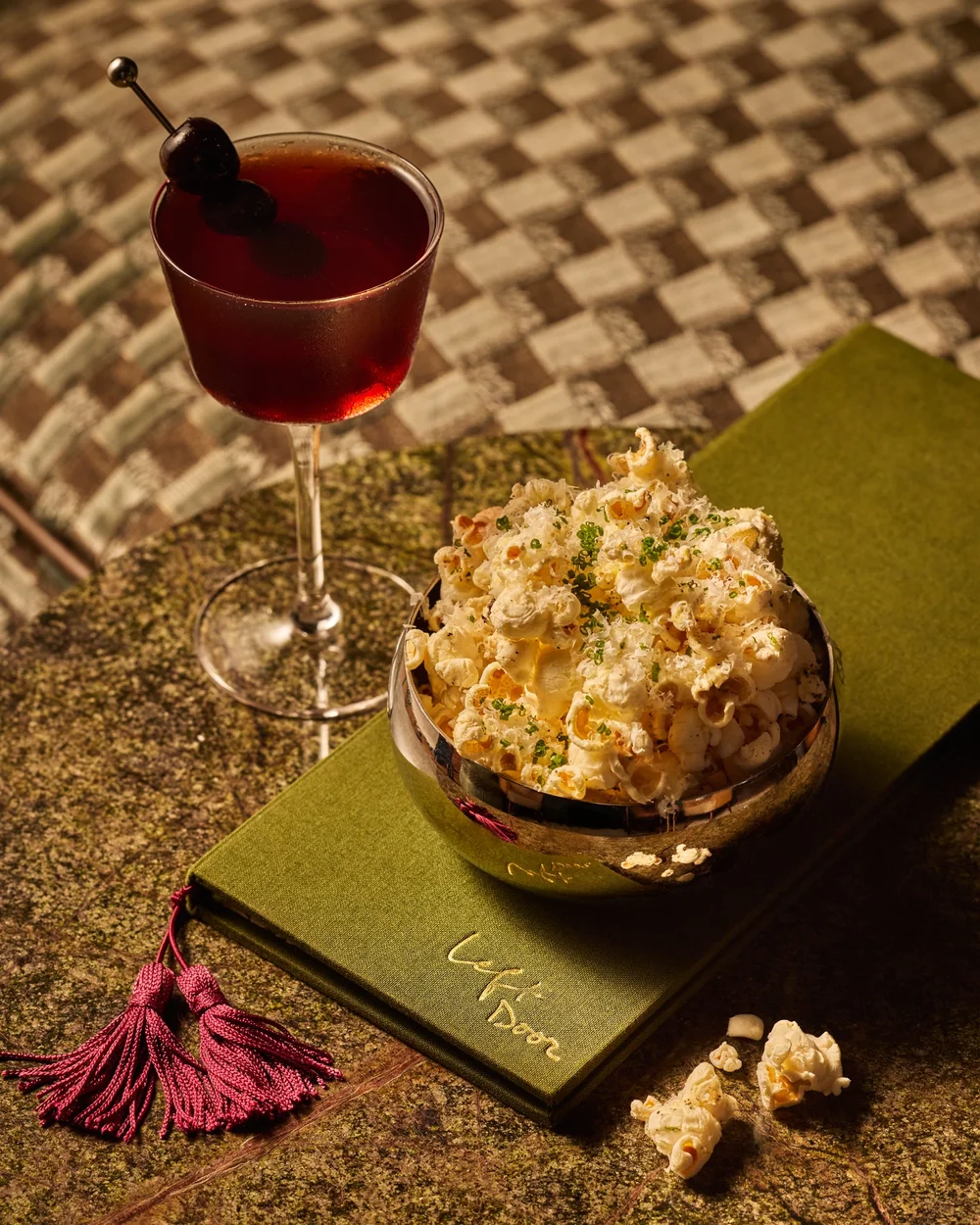 A bowl of popcorn beside a Manhattan cocktail