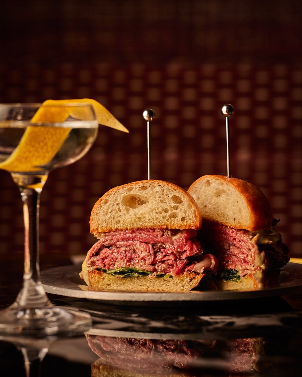 A sandwich on a plate beside a martini