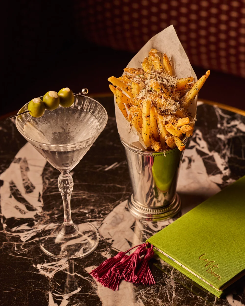 French fries beside a martini with three olives and a green menu