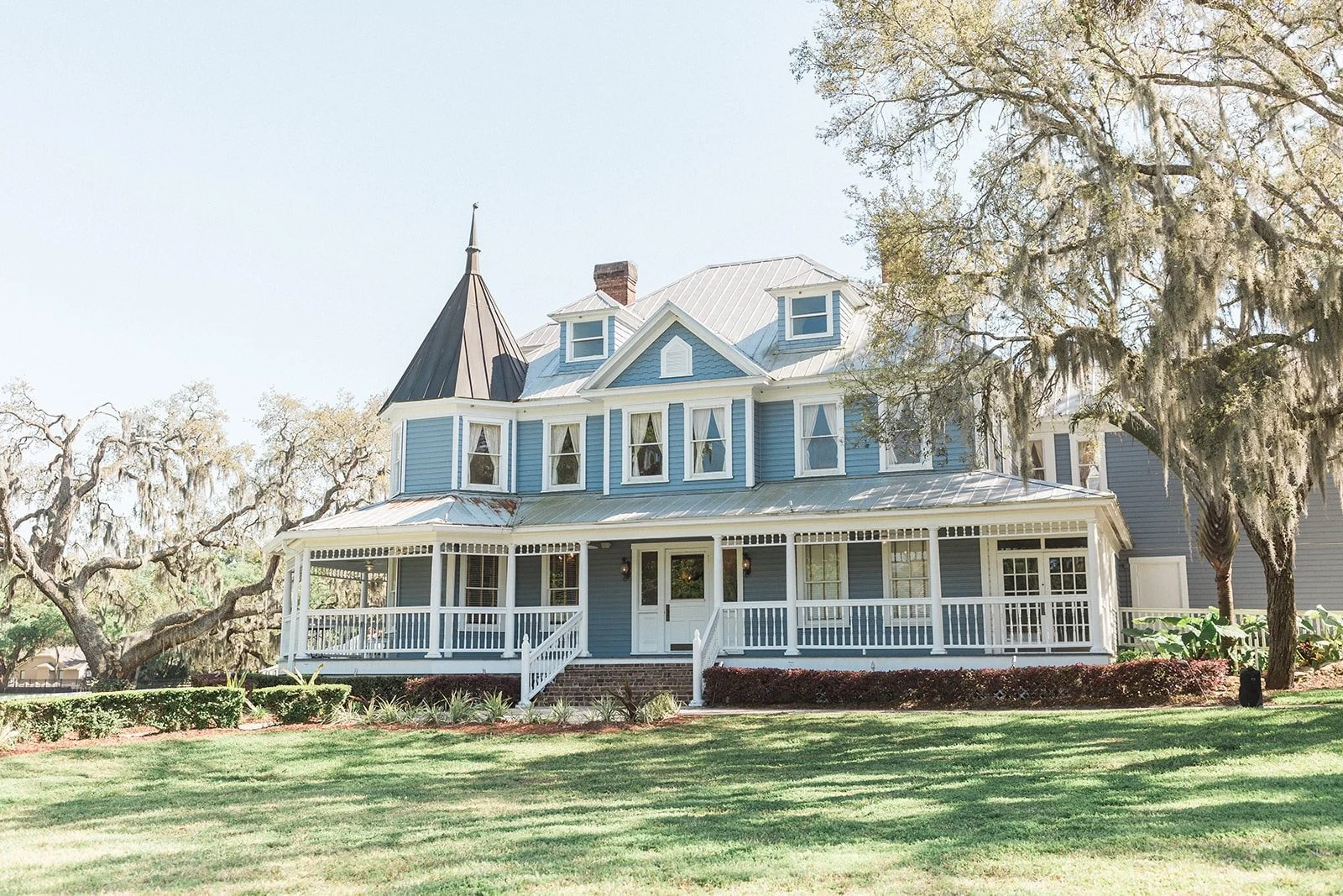 Blue paneled house with white doors and windows on green shaded lawn