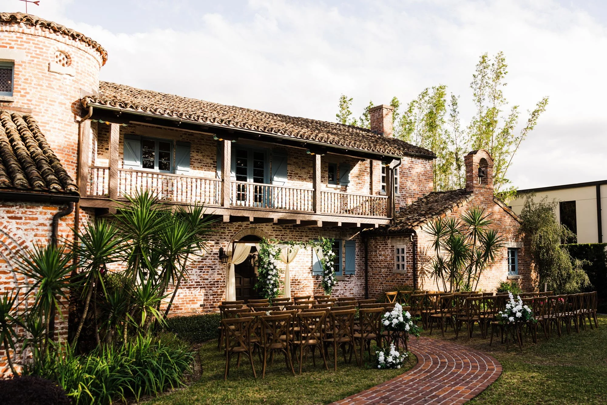 Brick-walled historic house with wood porch and wood chairs in lawn