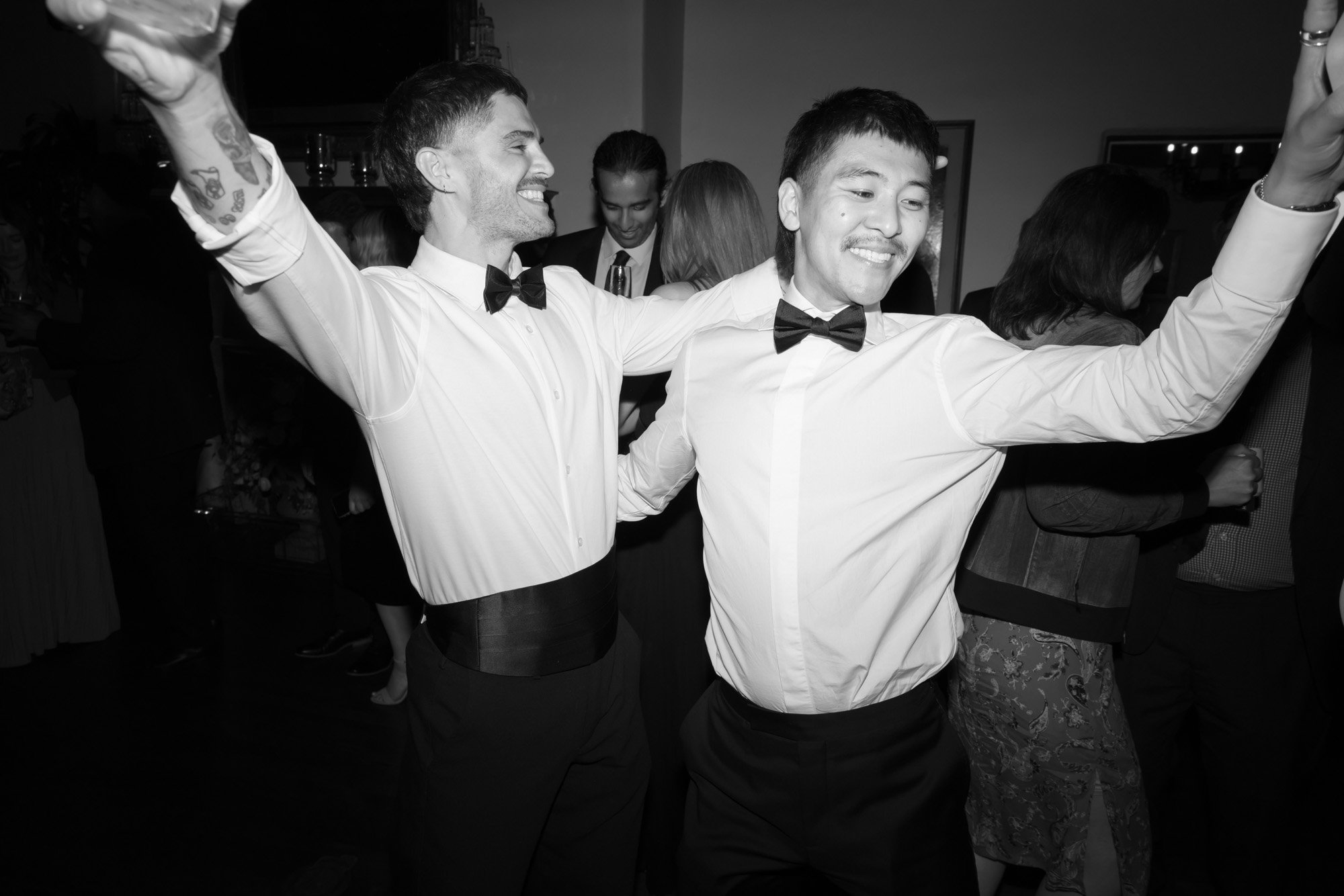 Black and white candid groomsmen moment during a luxury California wedding reception. Same sex wedding photography