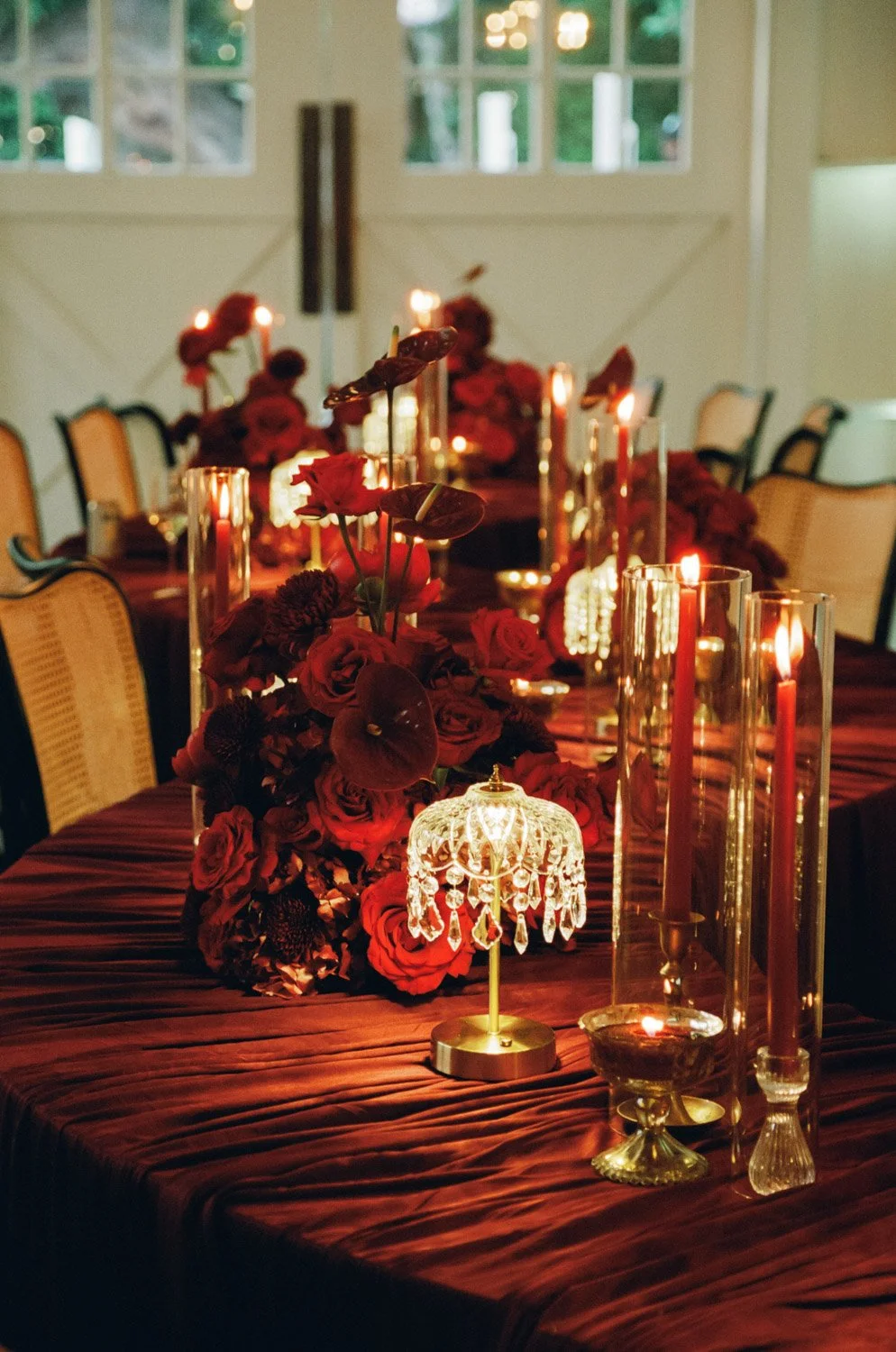 Elegant dining table decorated with red roses, candles, and a small crystal chandelier lamp.