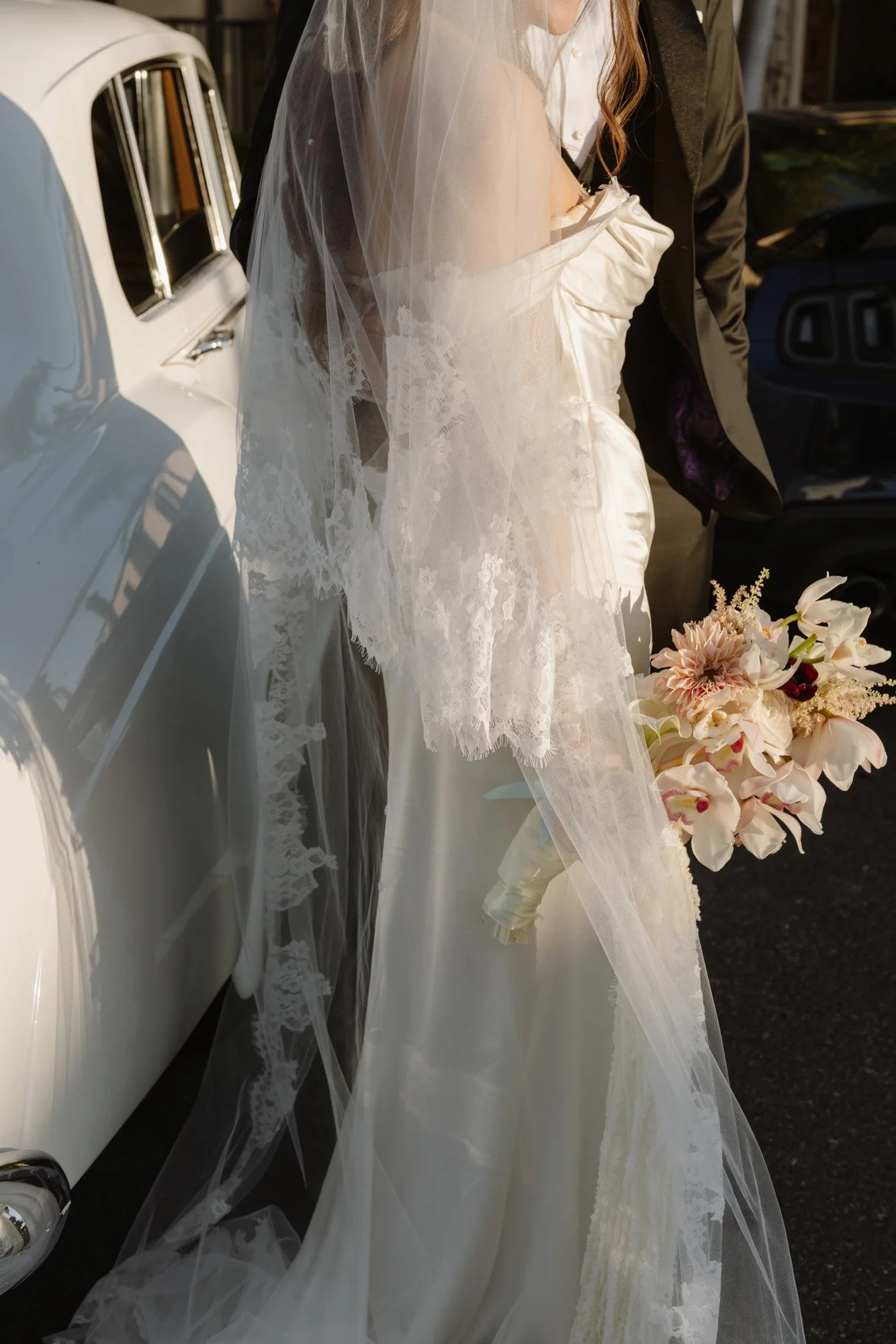 Bridal veil and bouquet detail photographed in a nostalgic film wedding style set against a vintage car, at the Ebell of Long Beach