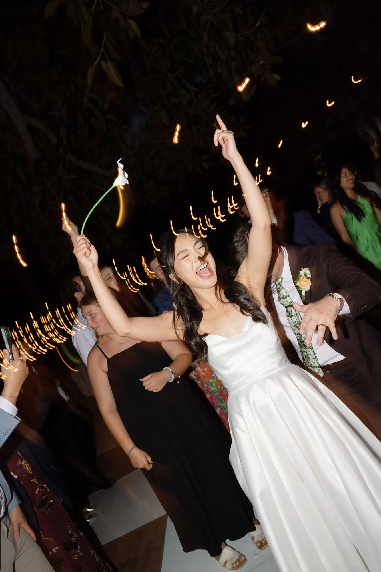 Bride dancing with sparklers during a lively documentary-style California wedding reception