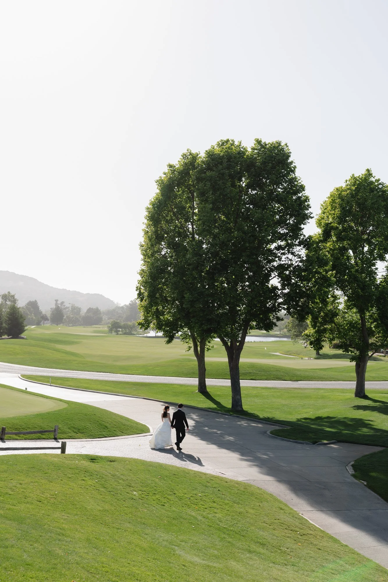 Wide landscape wedding portrait of couple walking through a California estate venue