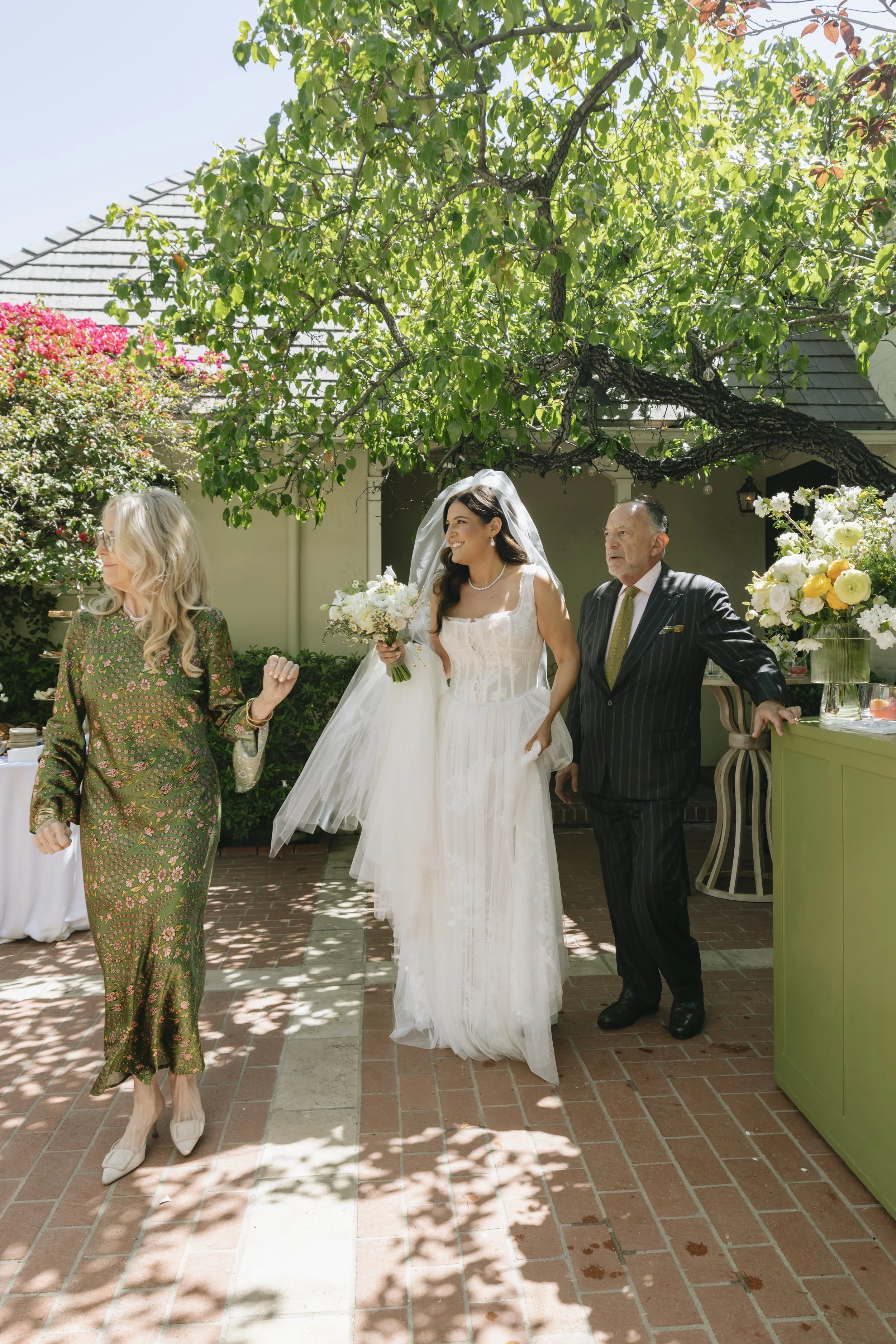Bride walking with her parents during a garden wedding processional in California