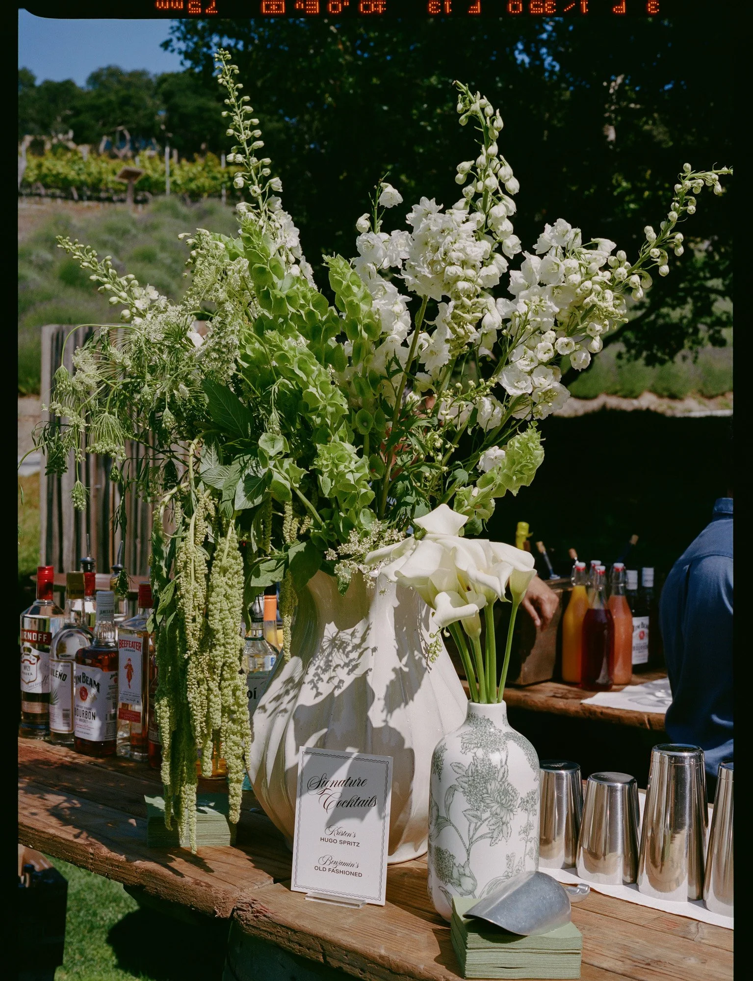 Wedding bar with white floral installation and bottles at a luxury California reception on medium format film photography.