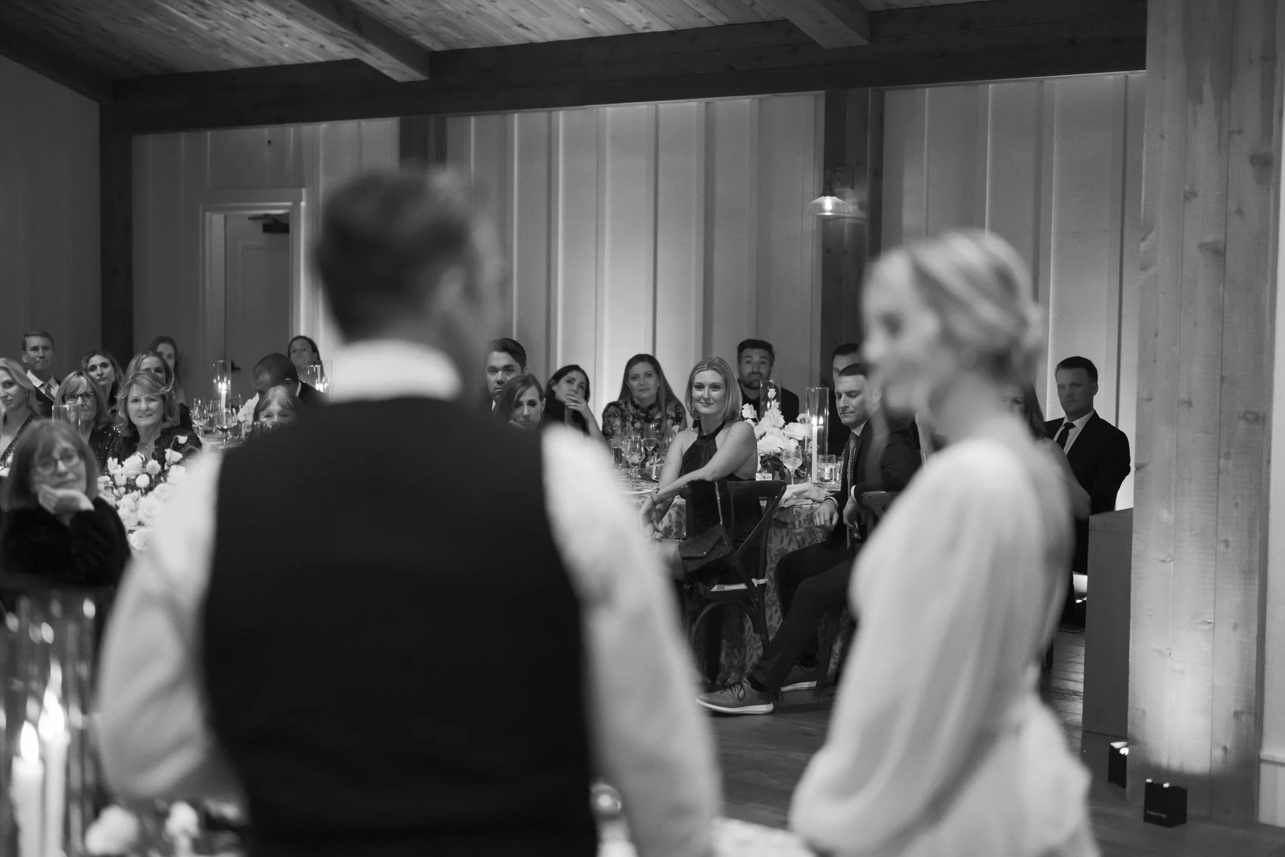 Documentary-style Black and white candid wedding reception speech with guests gathered around at a Mattei's Tavern Wedding