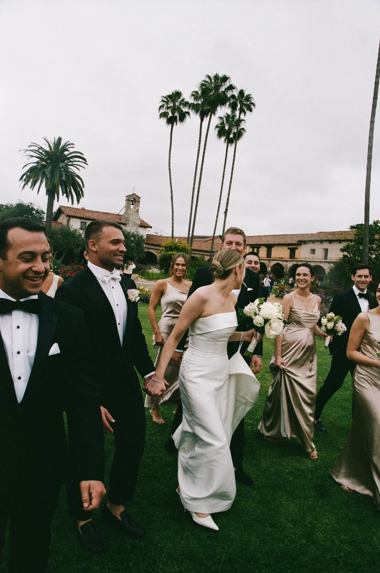 Bride walking with wedding party during an editorial documentary wedding moment at the Mission at San Juan Capistrano.