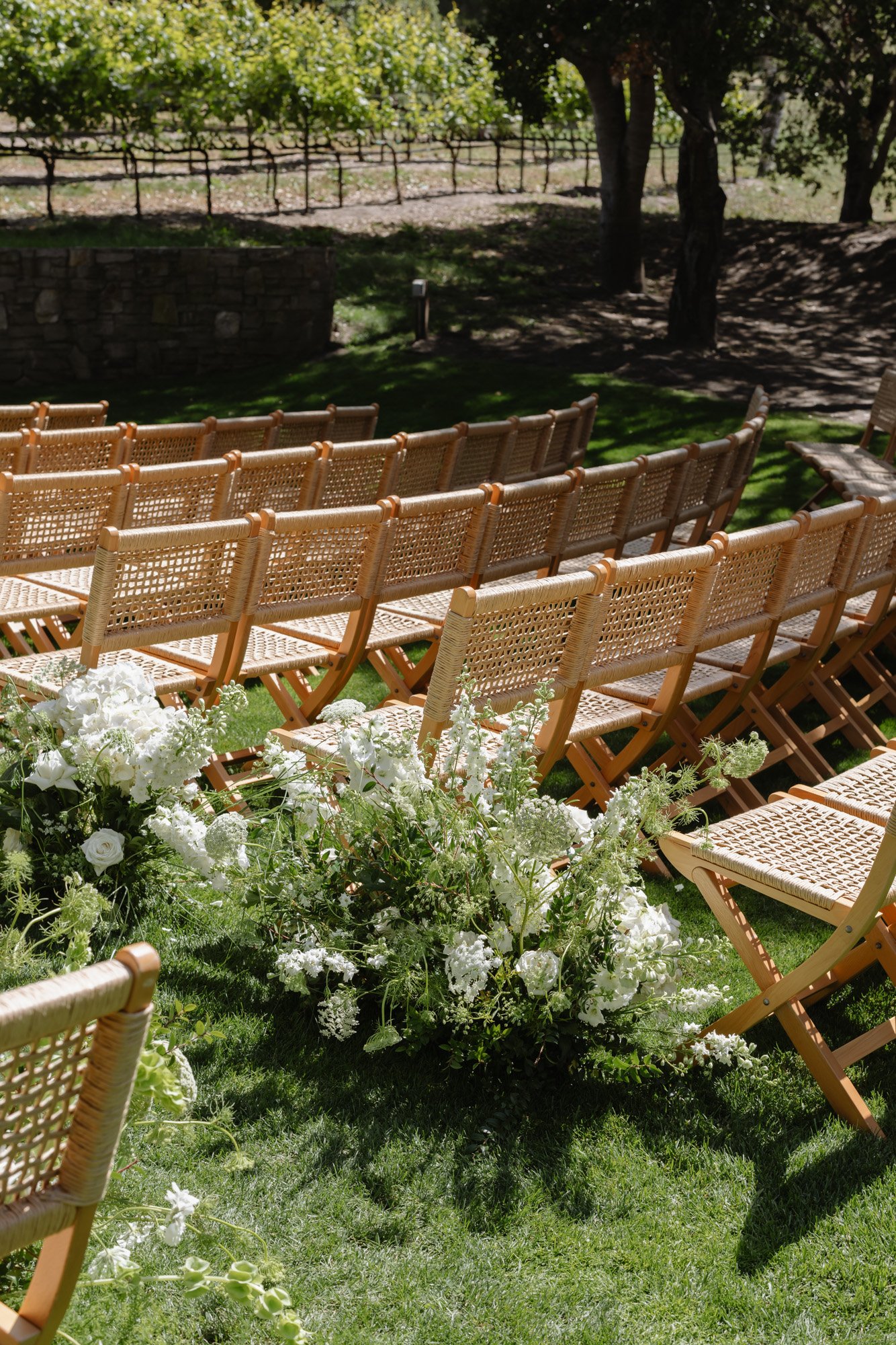 Garden wedding ceremony chairs lined with white florals in California