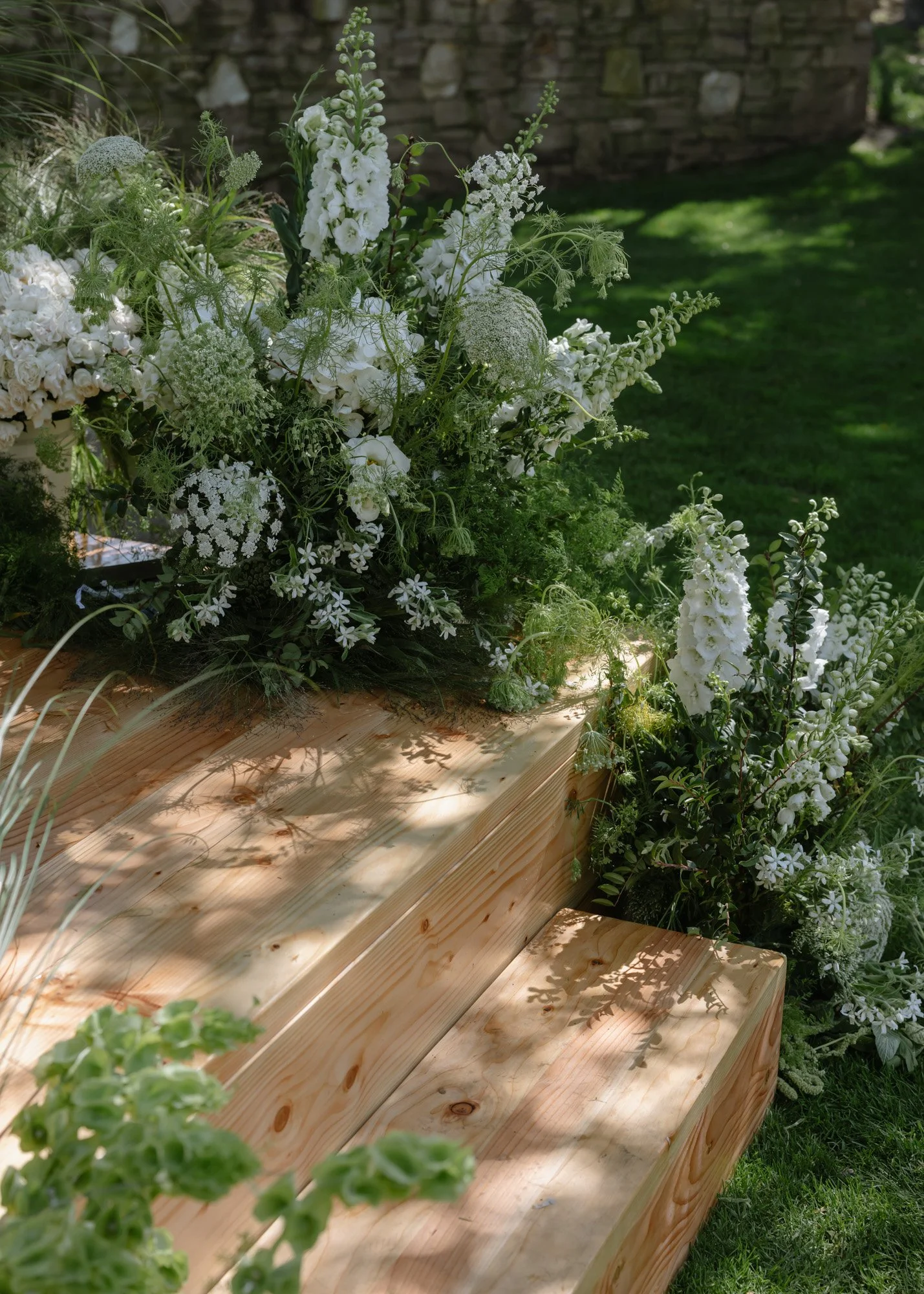 Lush white wedding ceremony florals surrounding a wooden aisle in California at the Carmel Valley Ranch documented on digital and film photography