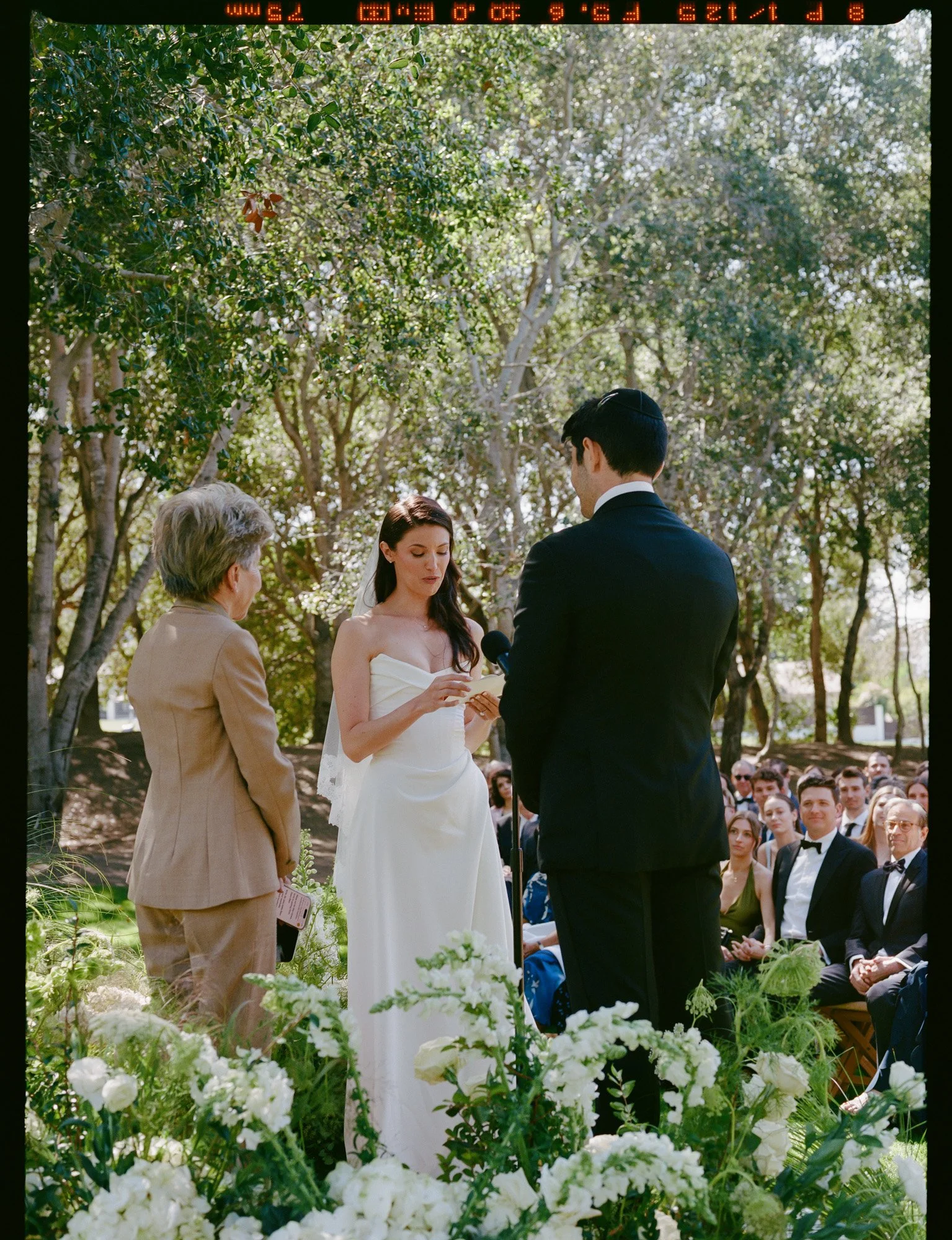 Outdoor wedding ceremony with lush greenery and documentary-style vows at a luxury California wedding venue, captured on medium format film