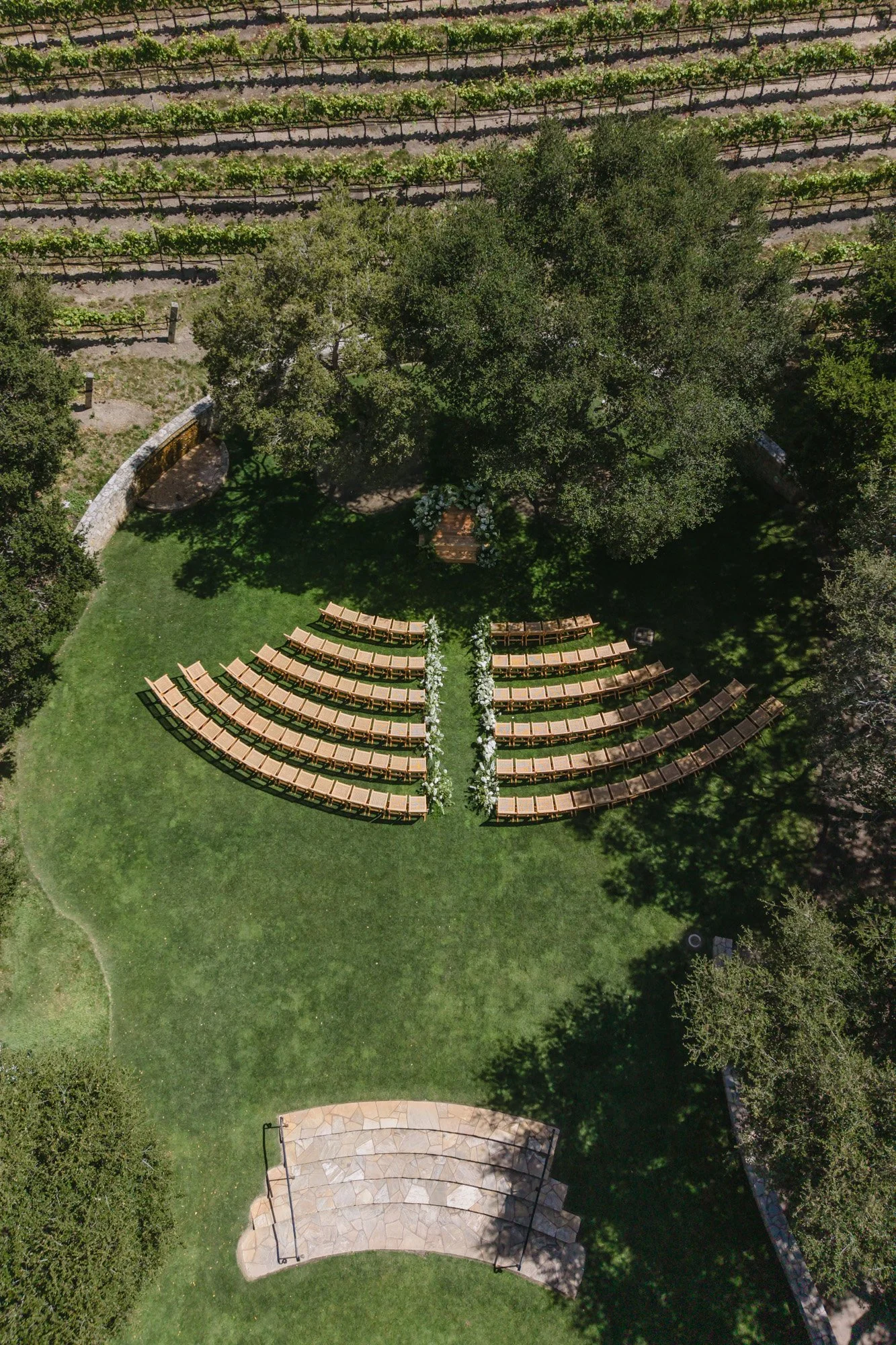 Aerial view of outdoor wedding ceremony seating beneath trees in California