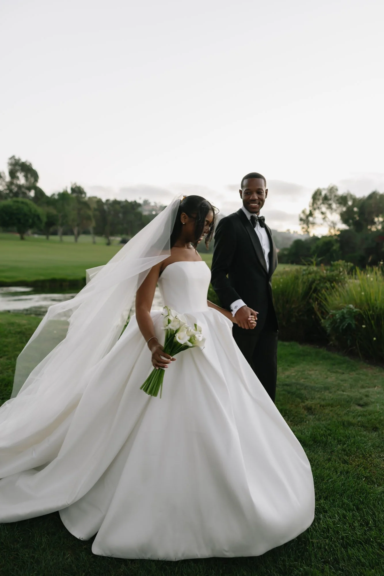 Bride and groom walking through golden light at a California estate wedding venue, documented in a Vogue, editorial-style