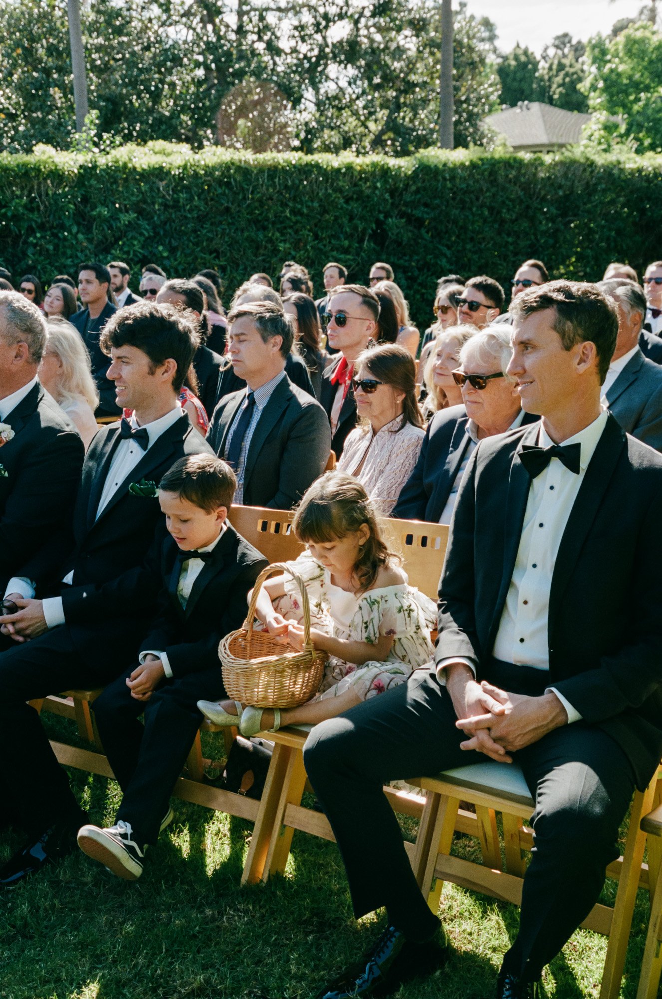 Wedding guests seated outdoors during a formal black-tie California ceremony captured on 35mm film photography