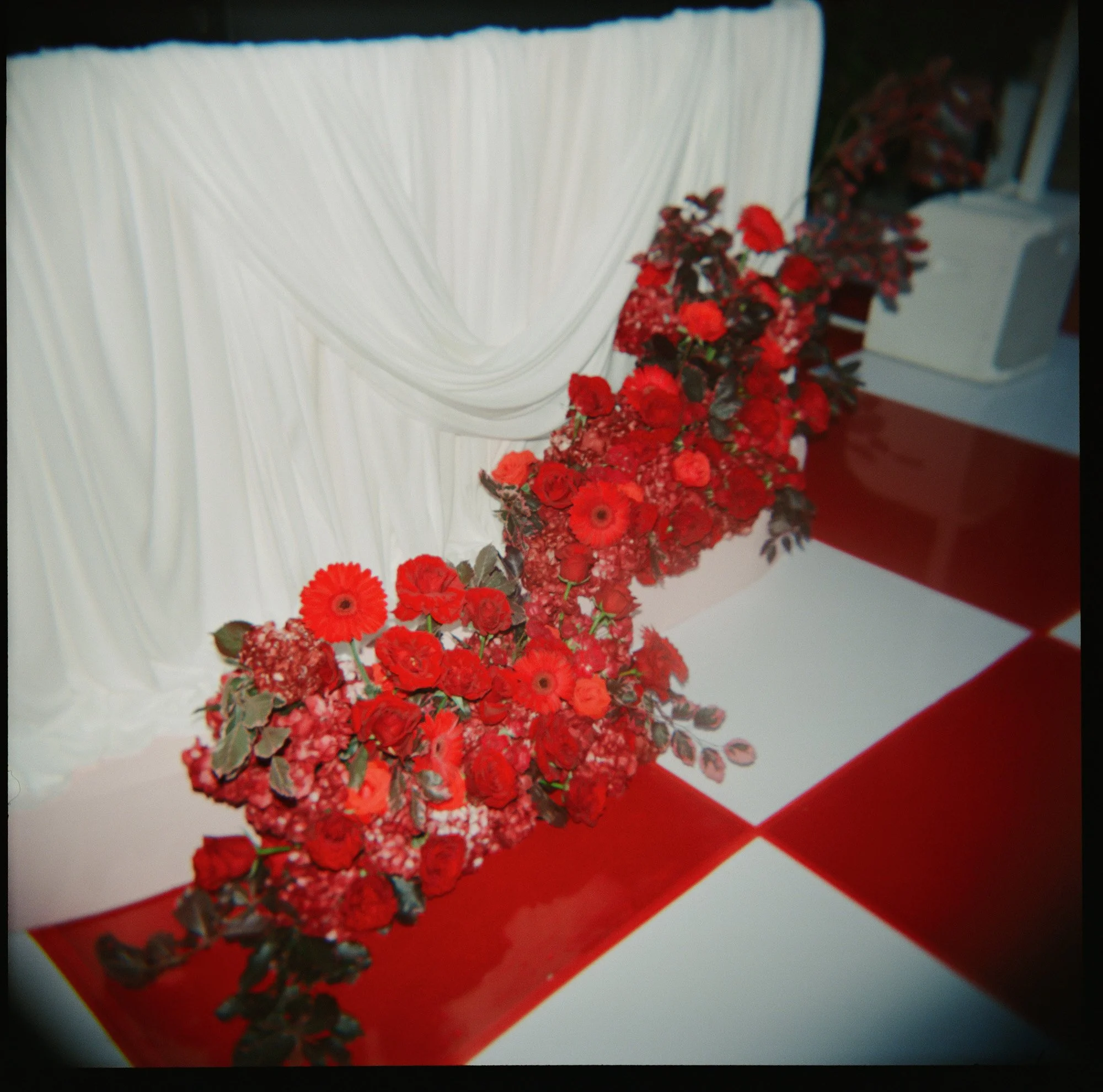 Red floral wedding installation with editorial checkered dance floor design captured on film