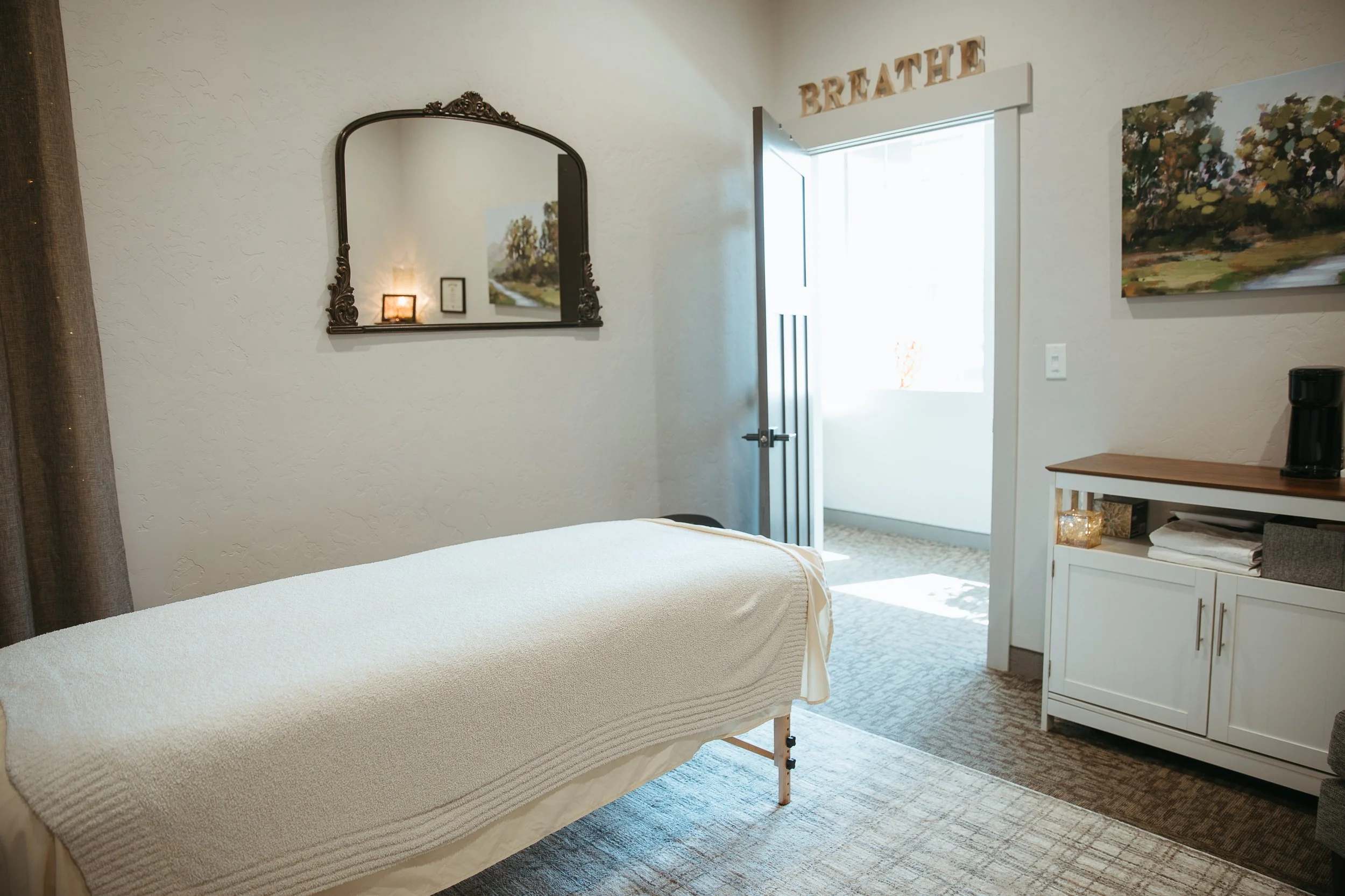 The Rounded Care treatment room in Meridian, Idaho, with a massage table, soft lighting, and an open doorway.