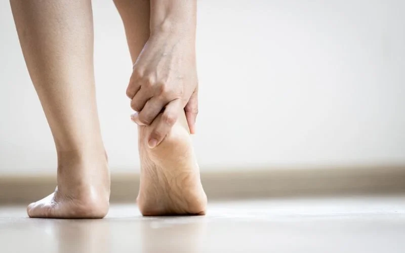 A person holding the heel of their foot with Plantar Fasciitis pain