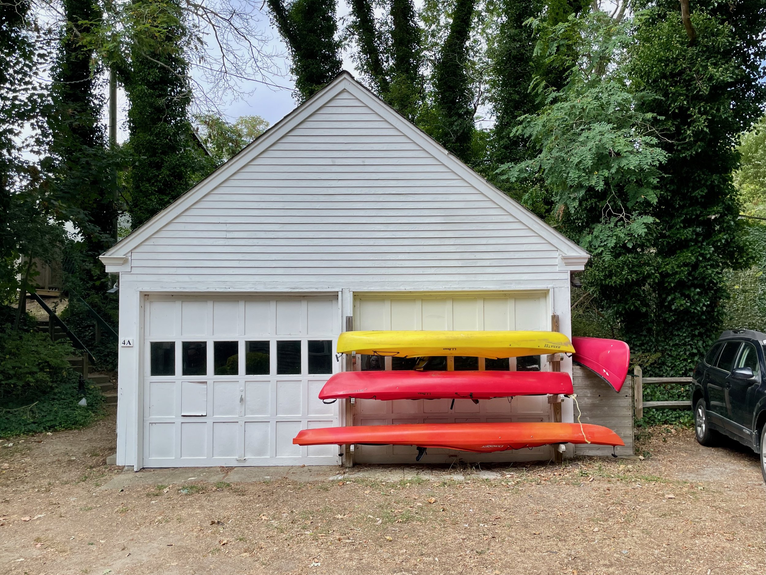 White garage with colorful kayaks in front.