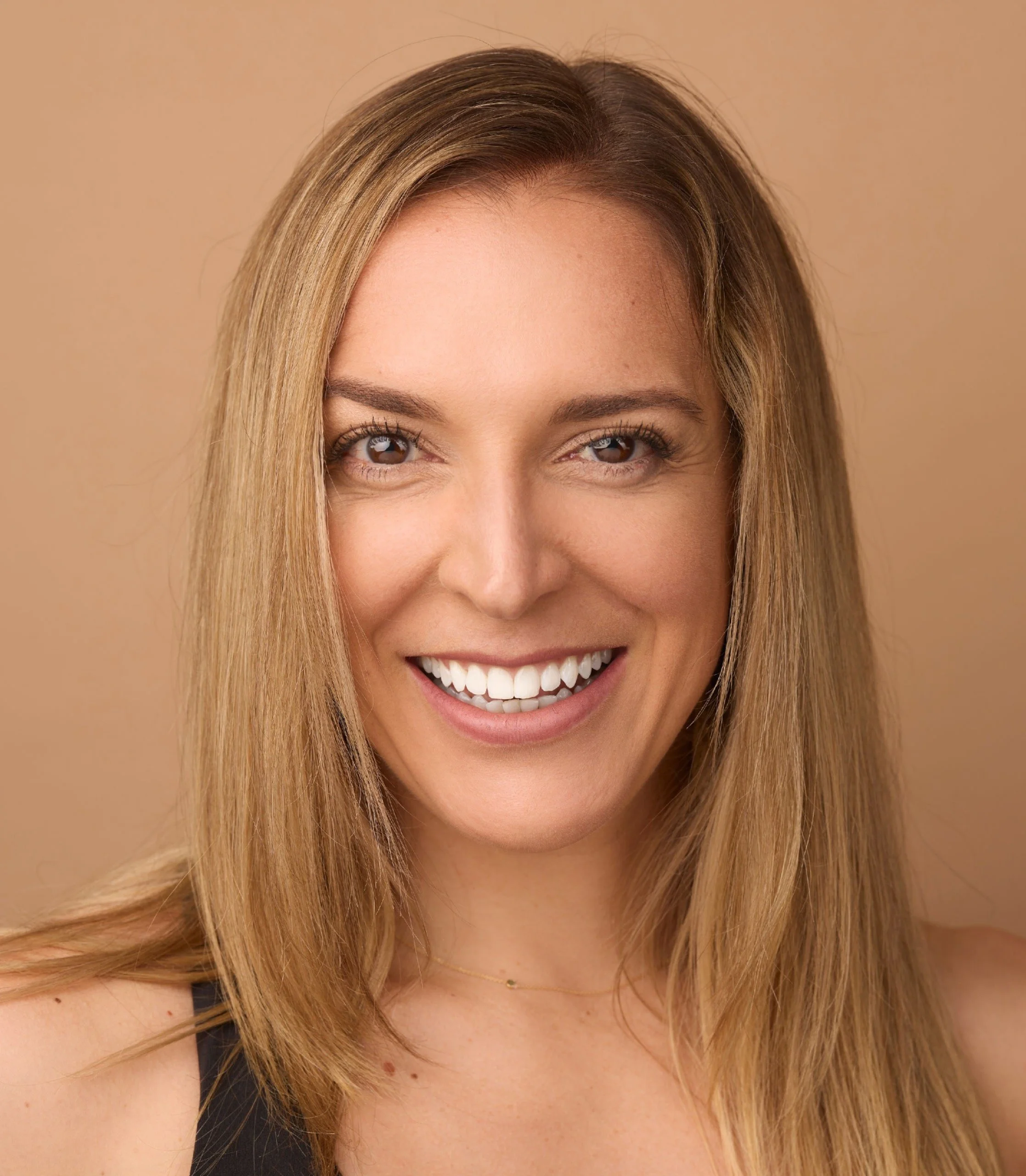 Heidi Pasch smiling in a professional headshot, photographed against a warm neutral background.
