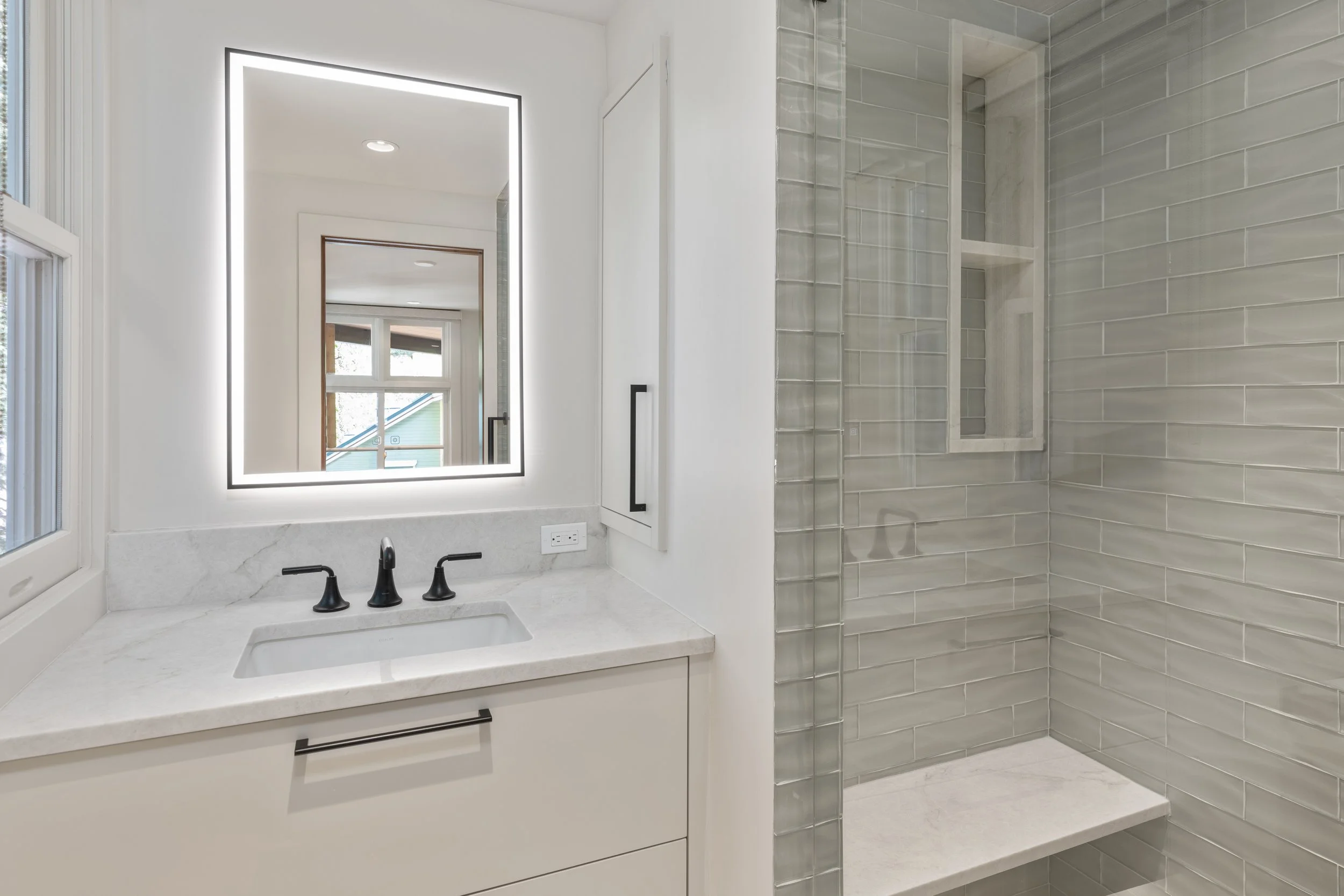 Guest bathroom with glass tile, walk-in shower, and backlit mirror. Telluride, Colorado home.