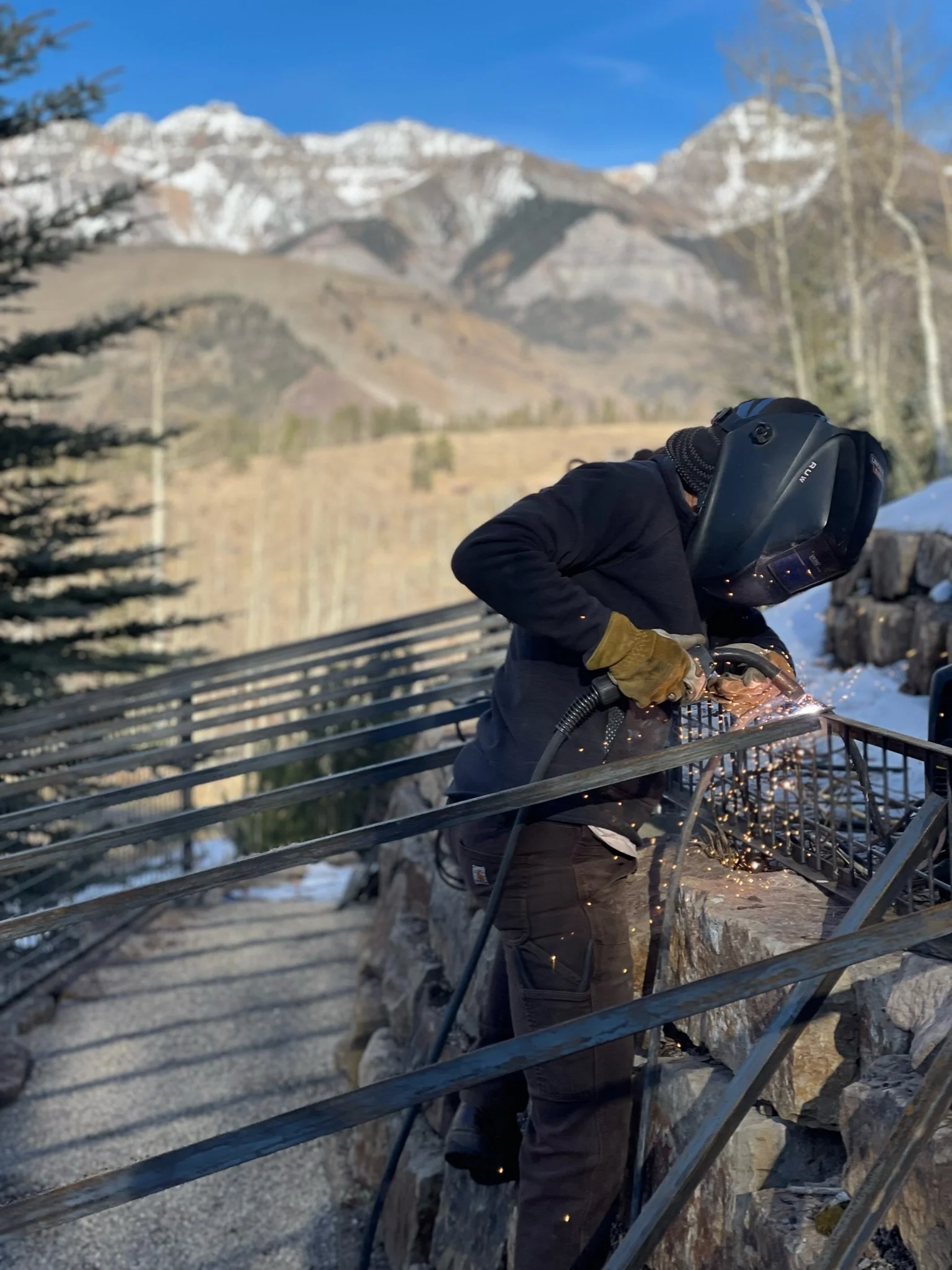 Custom home builder welding steel railing during winter construction, Telluride, Colorado.