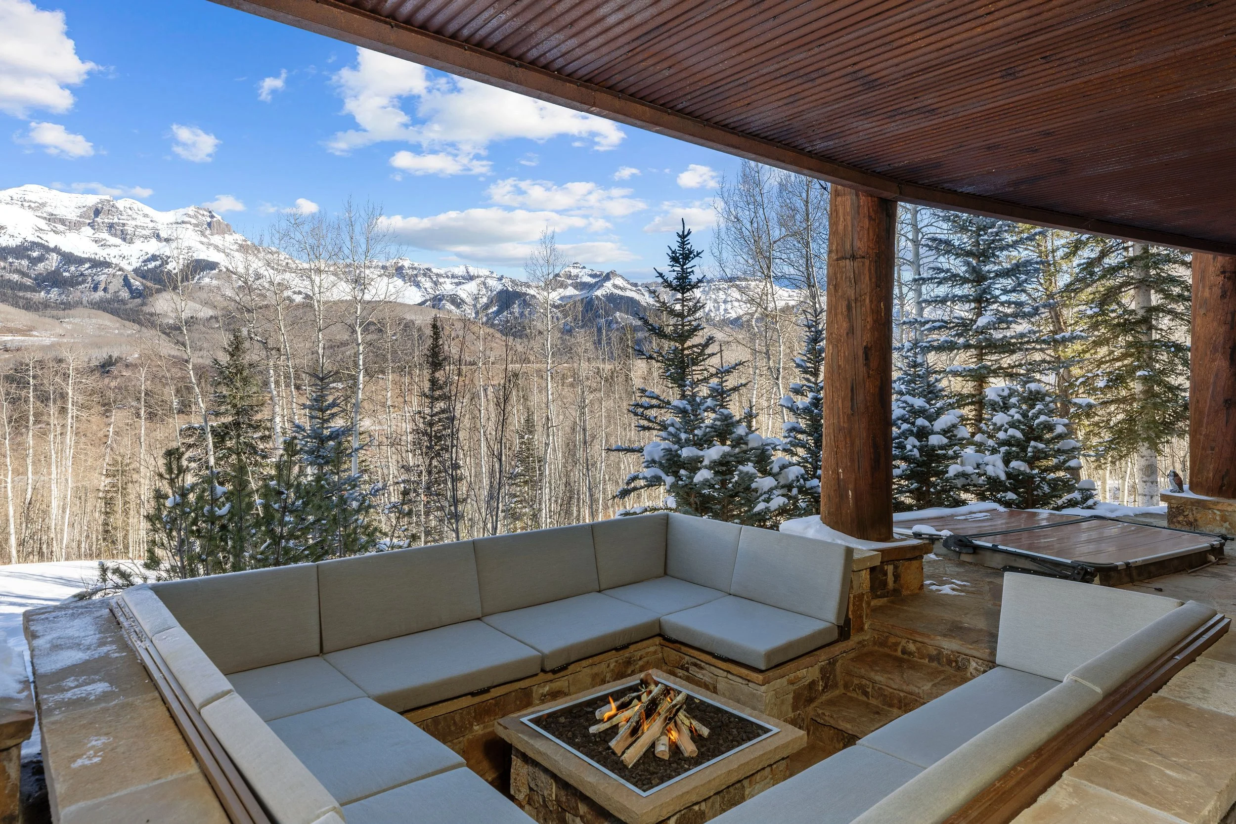 Covered patio with sunken fire pit seating and snow-capped mountain views, Telluride, Colorado.