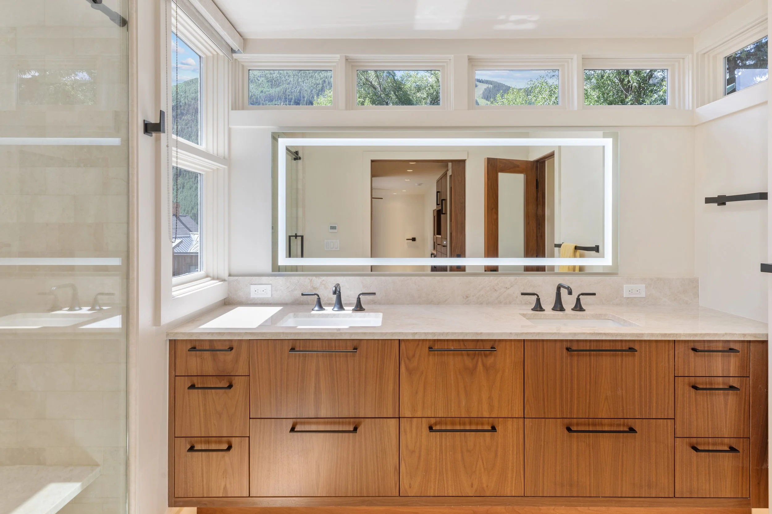 Primary bathroom with dual walnut vanity, quartzite countertop, and mountain view windows, Telluride, Colorado.