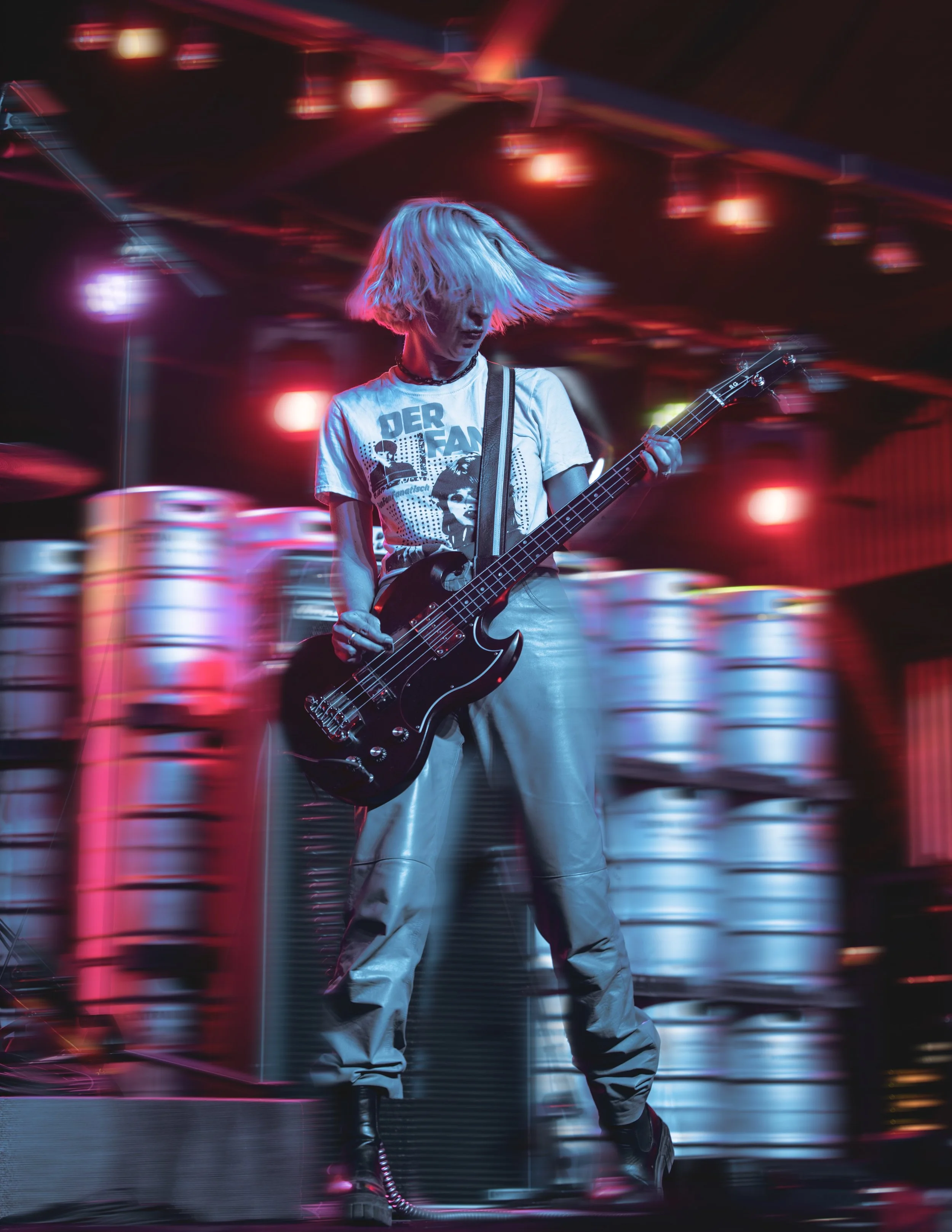 A female guitarist playing on stage with colorful lights and blurred background.