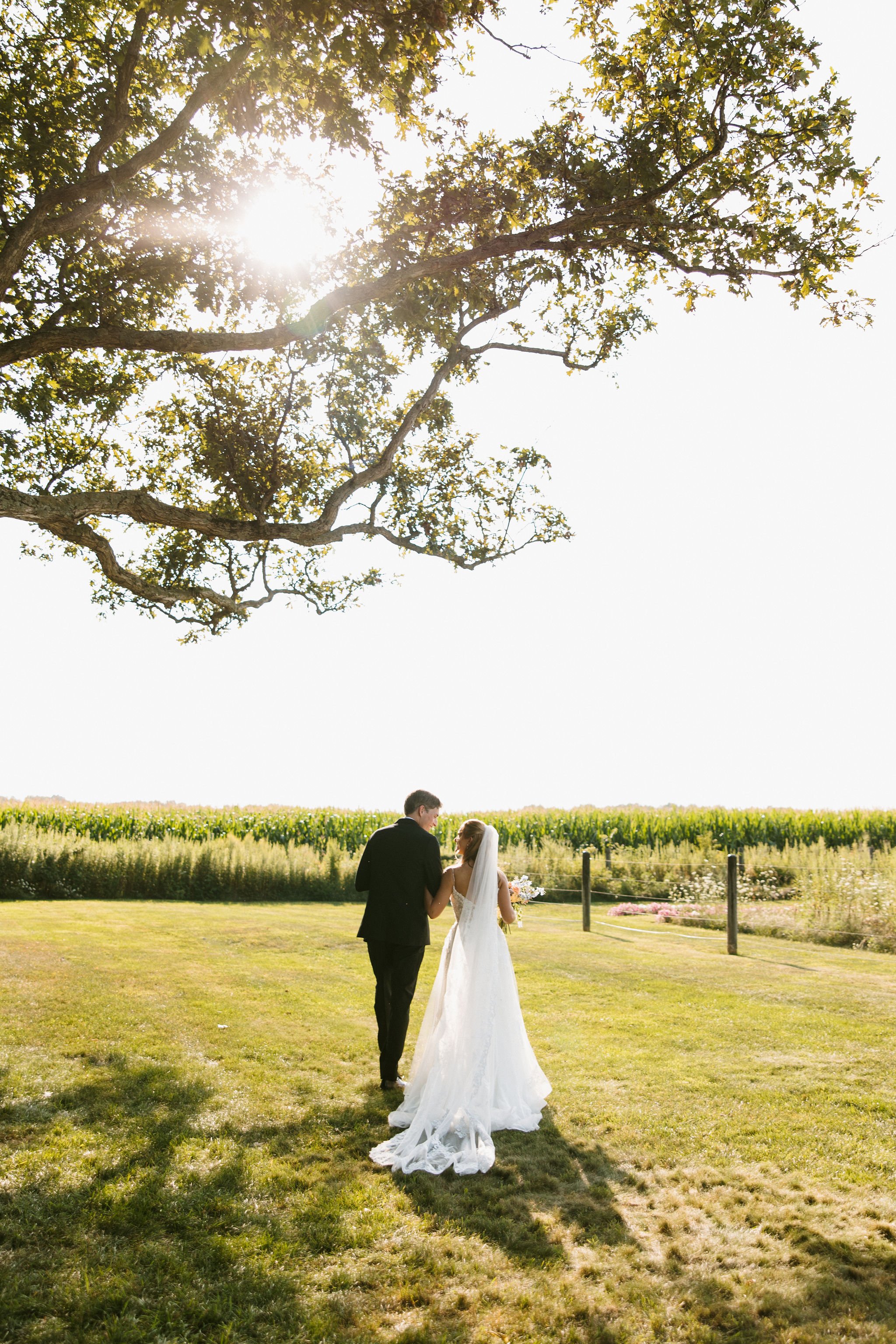 Newly married couple walking beneath the oak tree at Aspen & Alston wedding venue