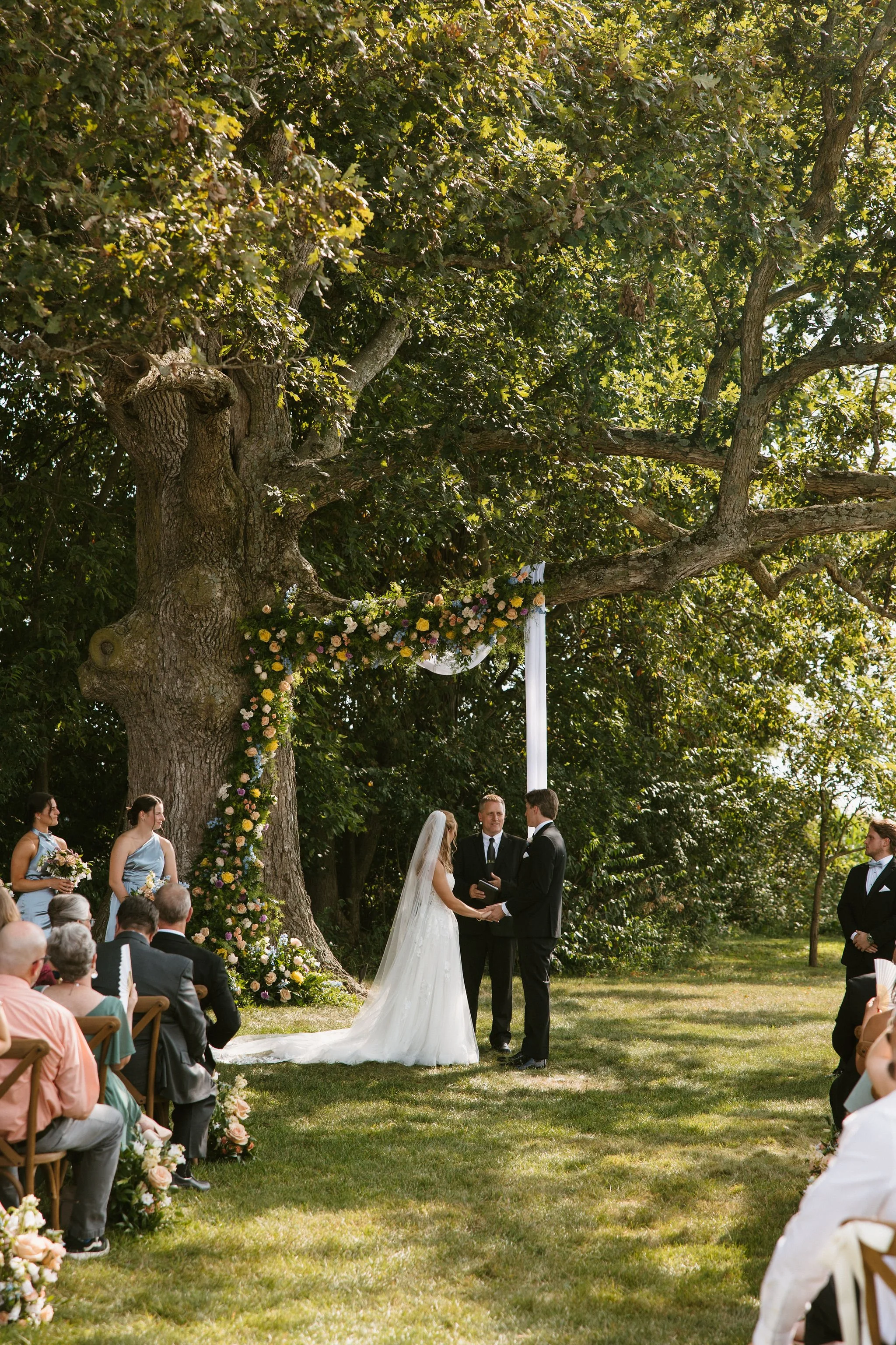Newly married couple walking beneath the oak tree at Aspen & Alston wedding venue