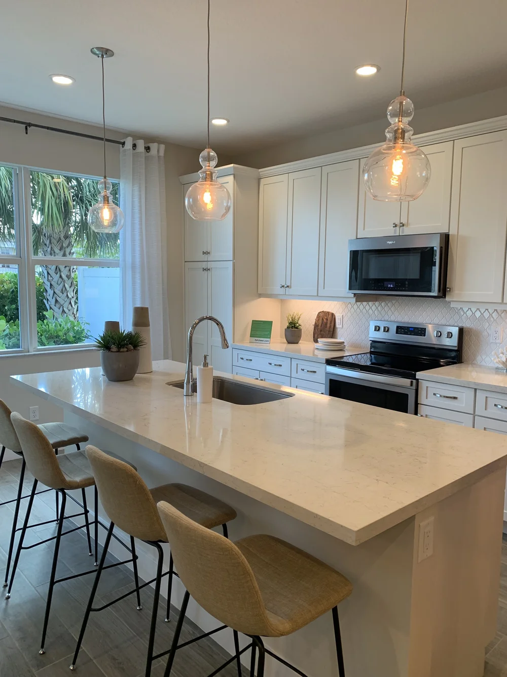 White shaker kitchen with an island, glass pendant lighting and custom cabinetry
