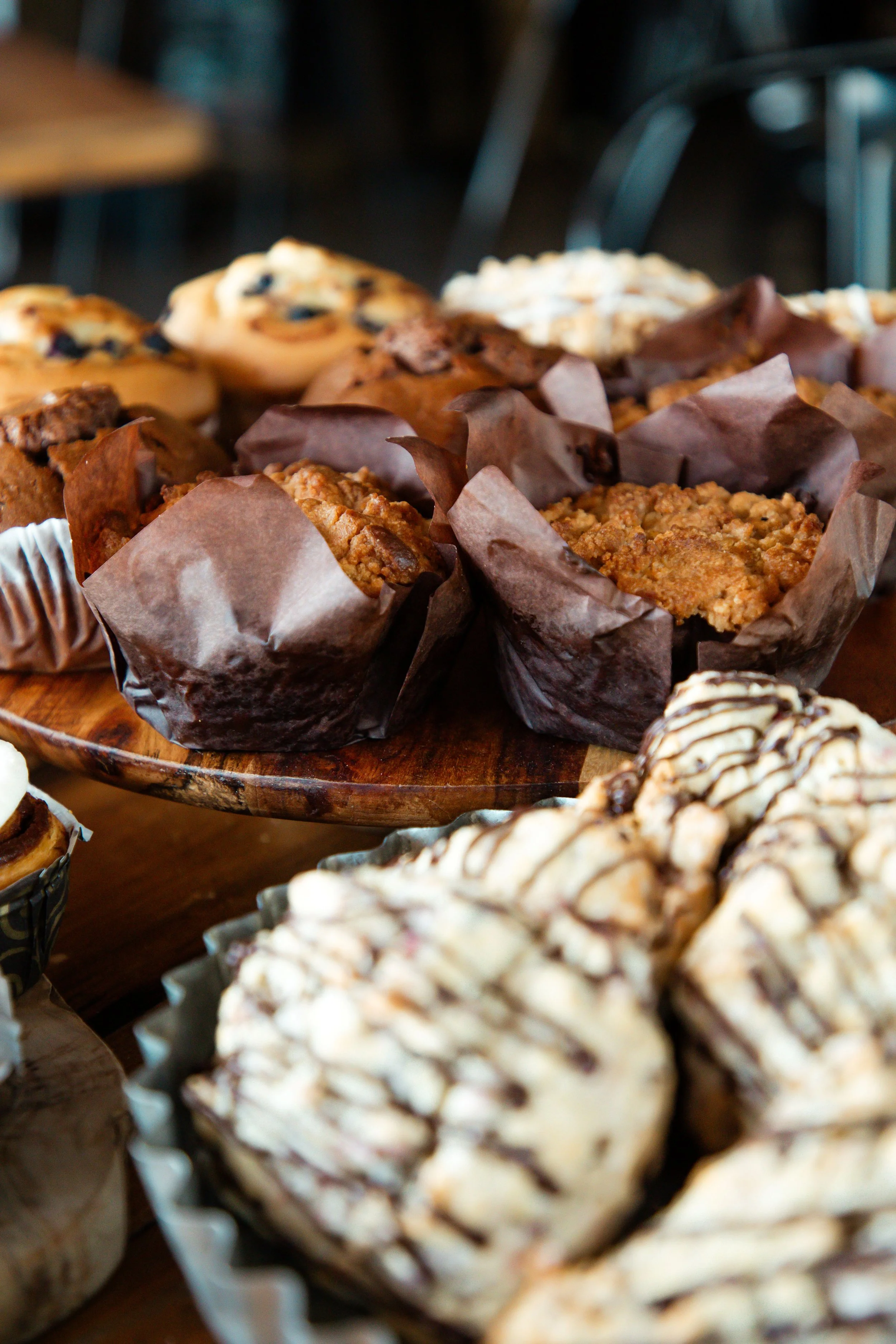 Assorted muffins on a wooden tray, including oatmeal, blueberry, and chocolate chip flavors.