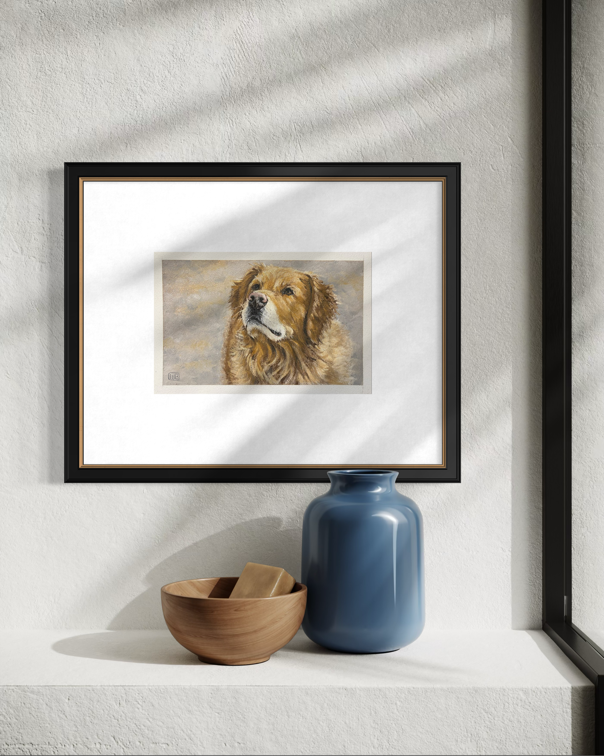 A framed painting of a golden retriever dog hangs on a textured white wall. There is a blue vase and a wooden bowl with a small wooden object on a white shelf below the painting.